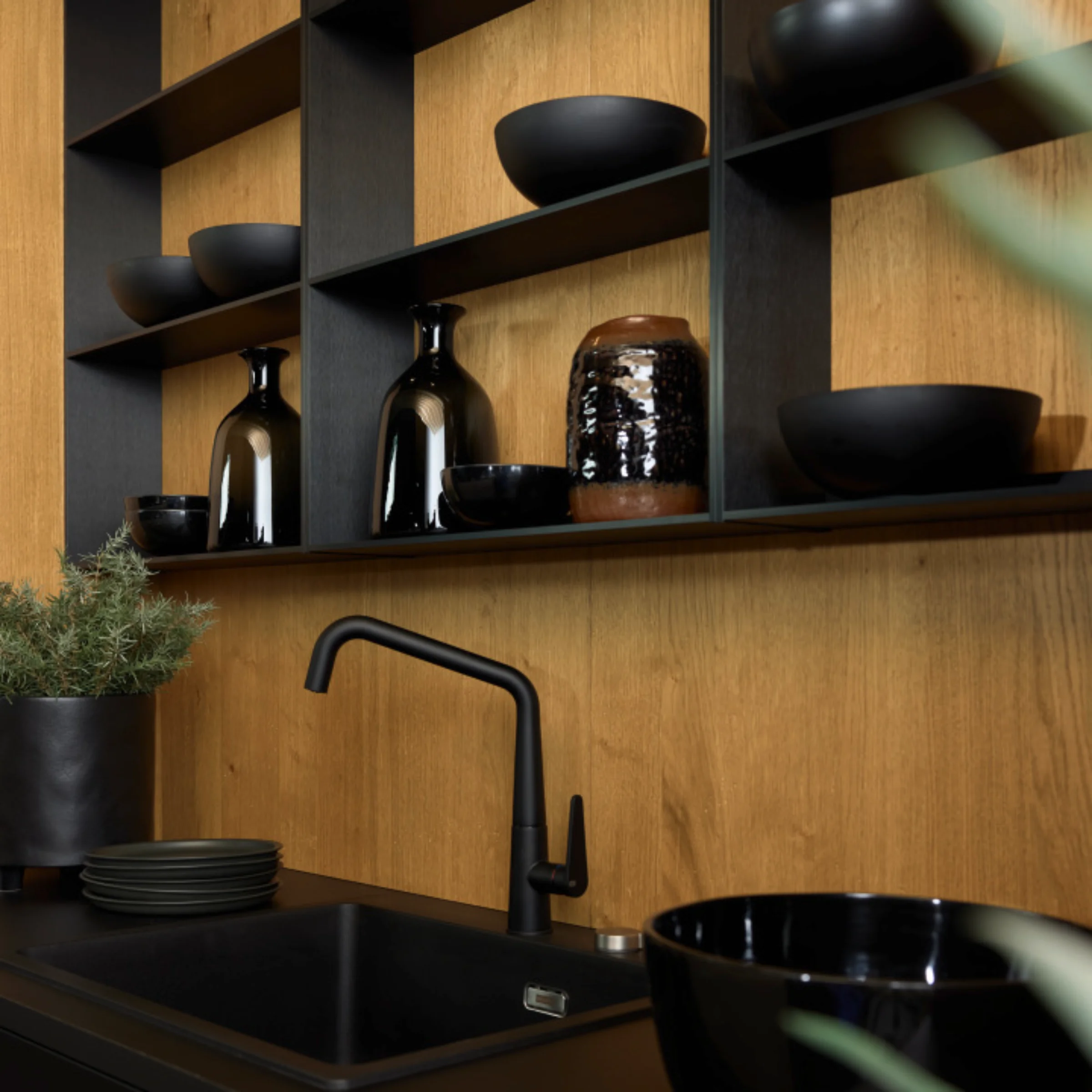 Eine moderne Küche mit schwarzer Arbeitsplatte und Holzregalen, gestaltet von Nolte Küchen.