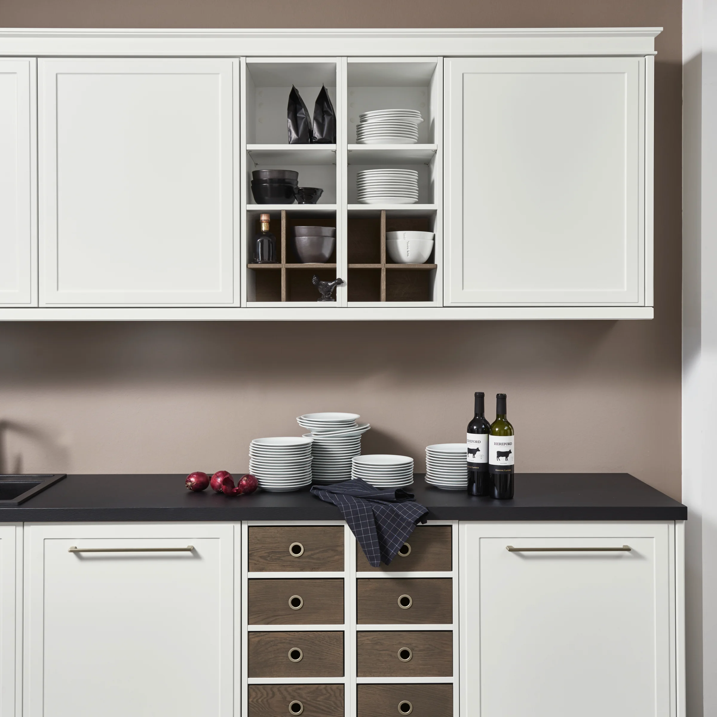 Una cocina moderna con armarios blancos y encimera oscura, presentada por Nolte Cocina.