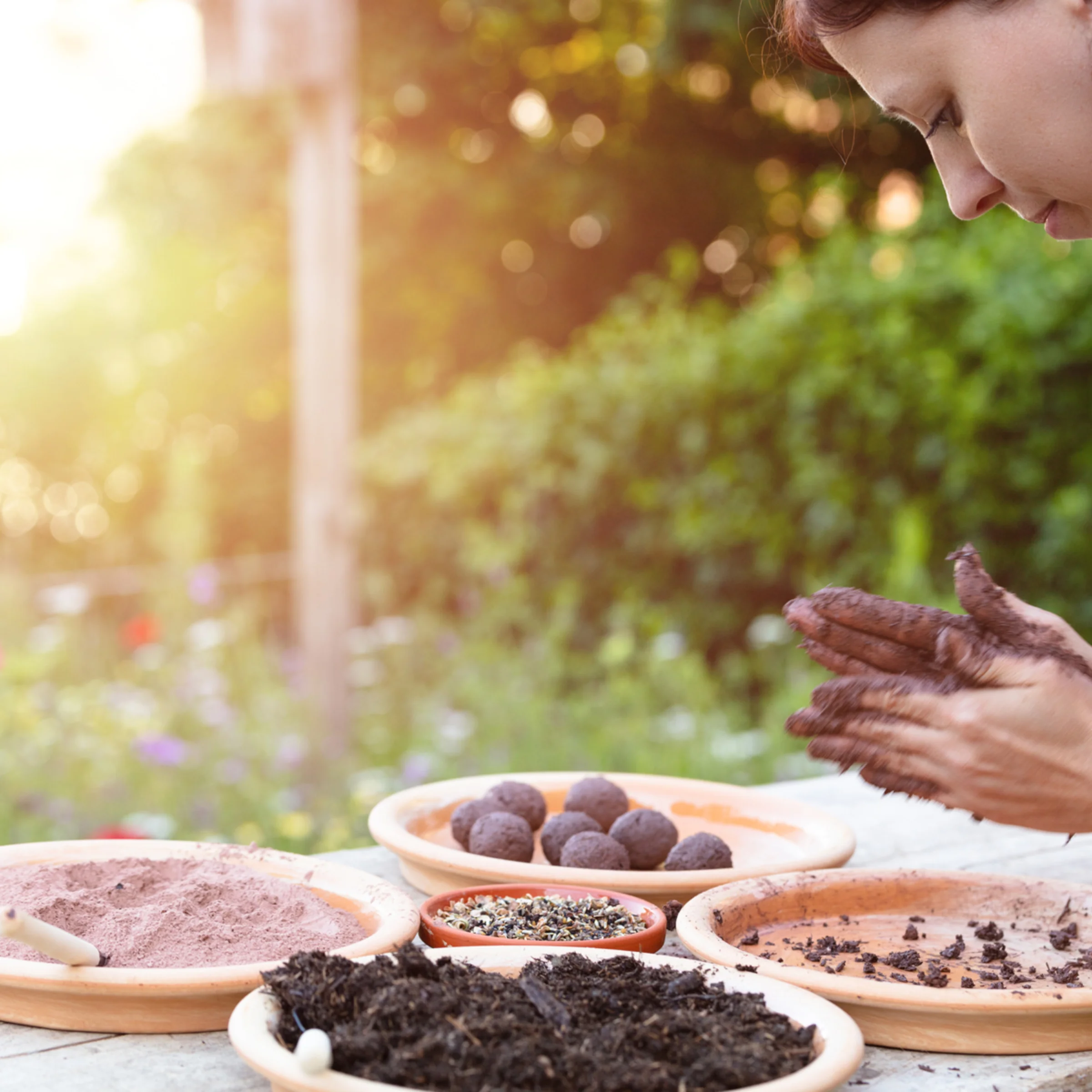 A woman making seed bombs from soil in a garden.