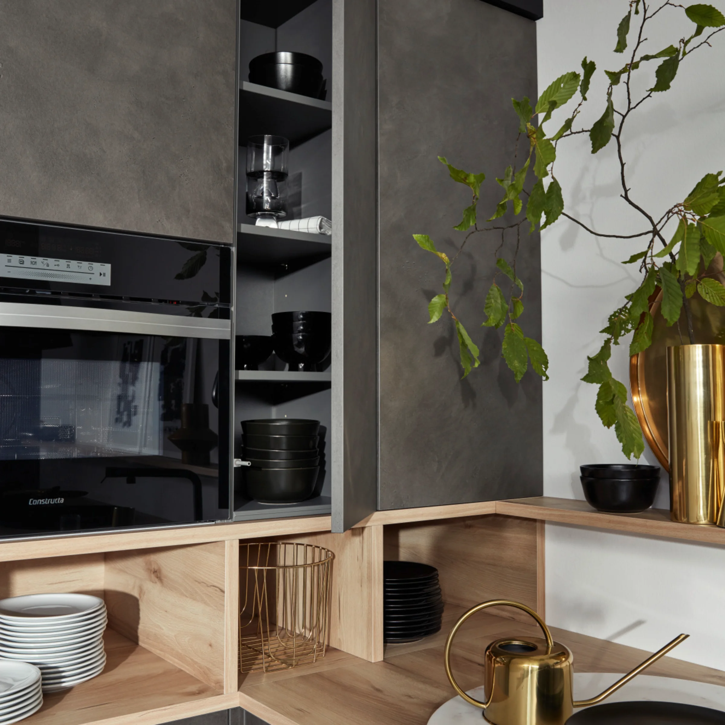 Eine moderne Küche mit grauen Schränken und Holzdetails, dekoriert mit Pflanzen. Nolte Küchen.