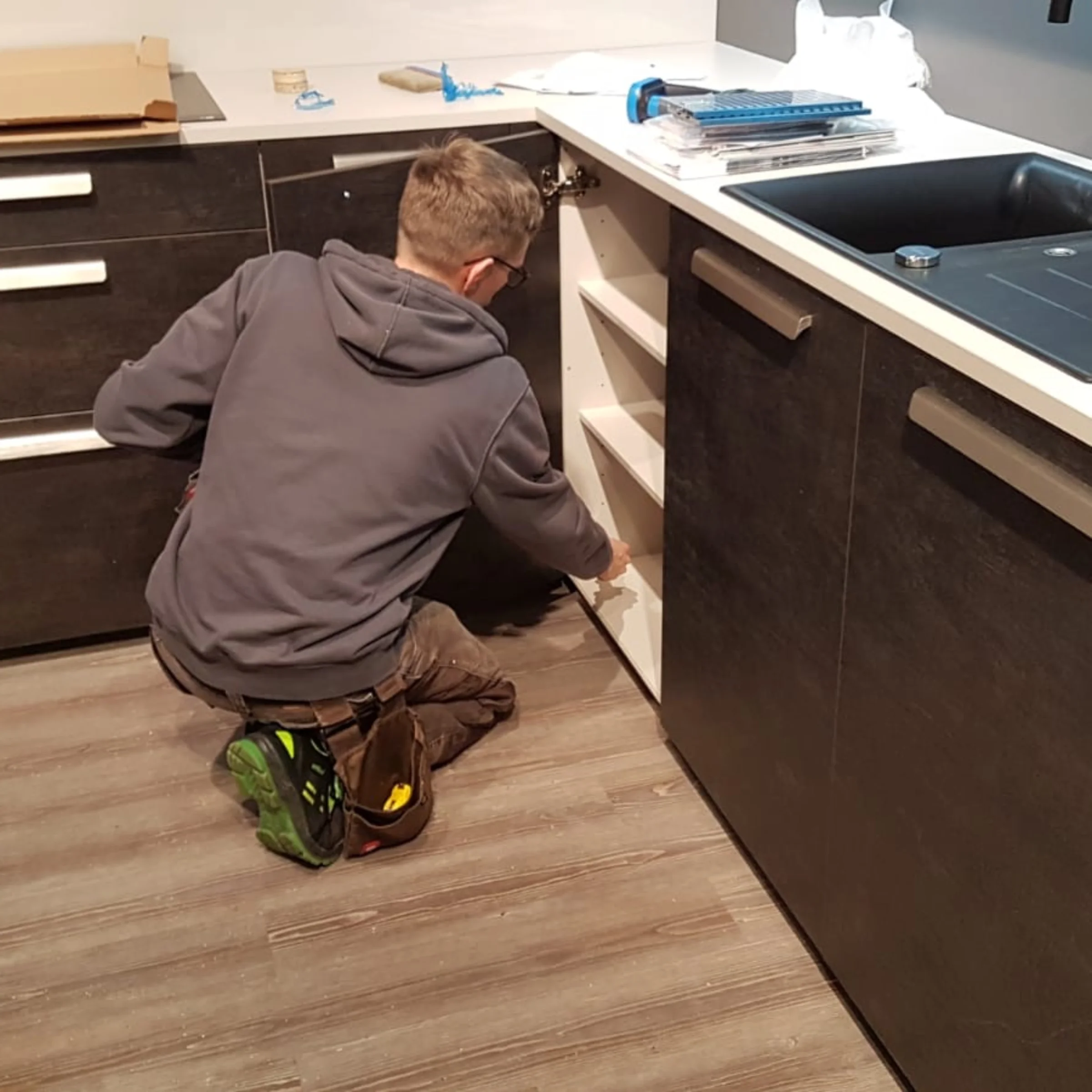 Eine Person arbeitet in einer modernen Küche mit dunklen Schränken. Nolte Küchen.