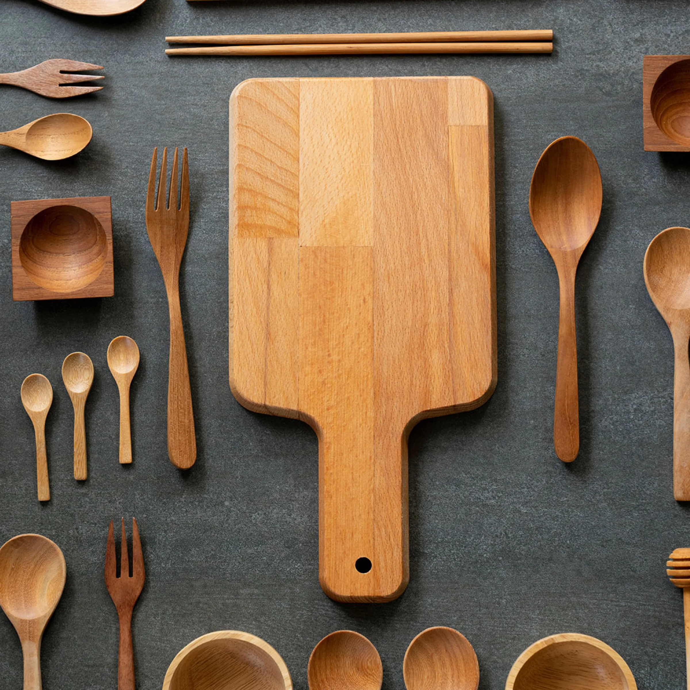Various wooden kitchen utensils and a cutting board arranged on a dark background, Nolte Kitchen.