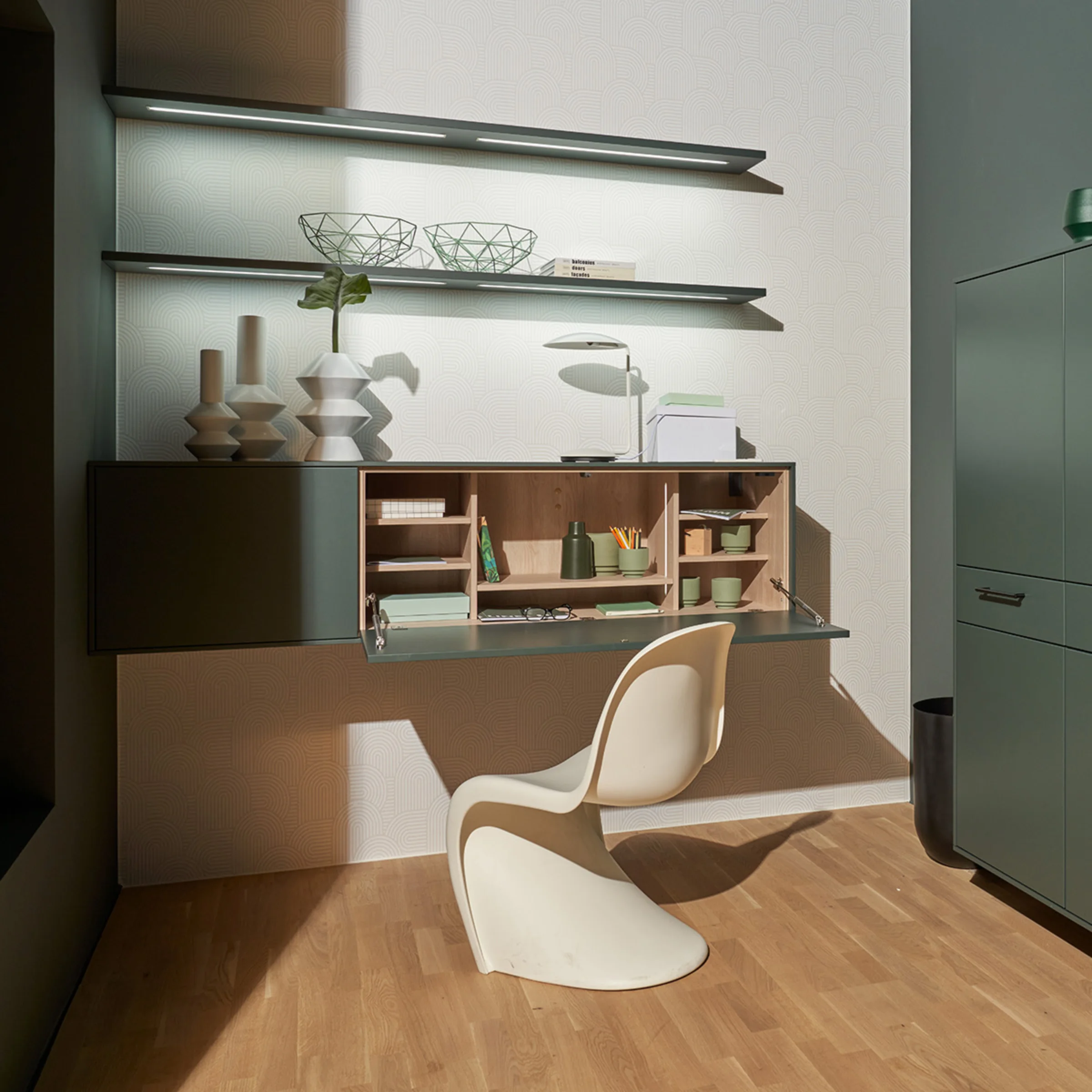 Ein stilvoller Arbeitsbereich mit grünem Schrank und Regal von Nolte Living.