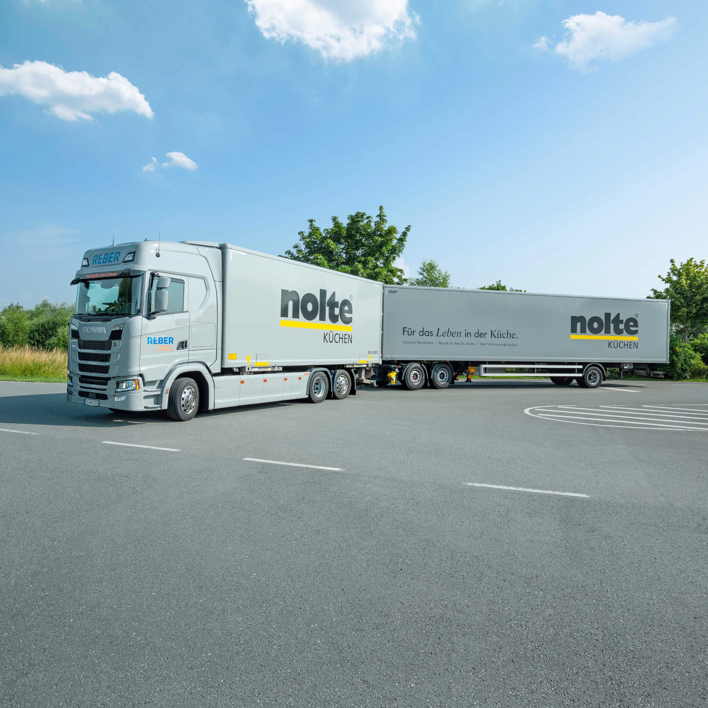 Ein LKW mit Aufschrift "Nolte Küchen" steht auf einem Parkplatz unter blauem Himmel.