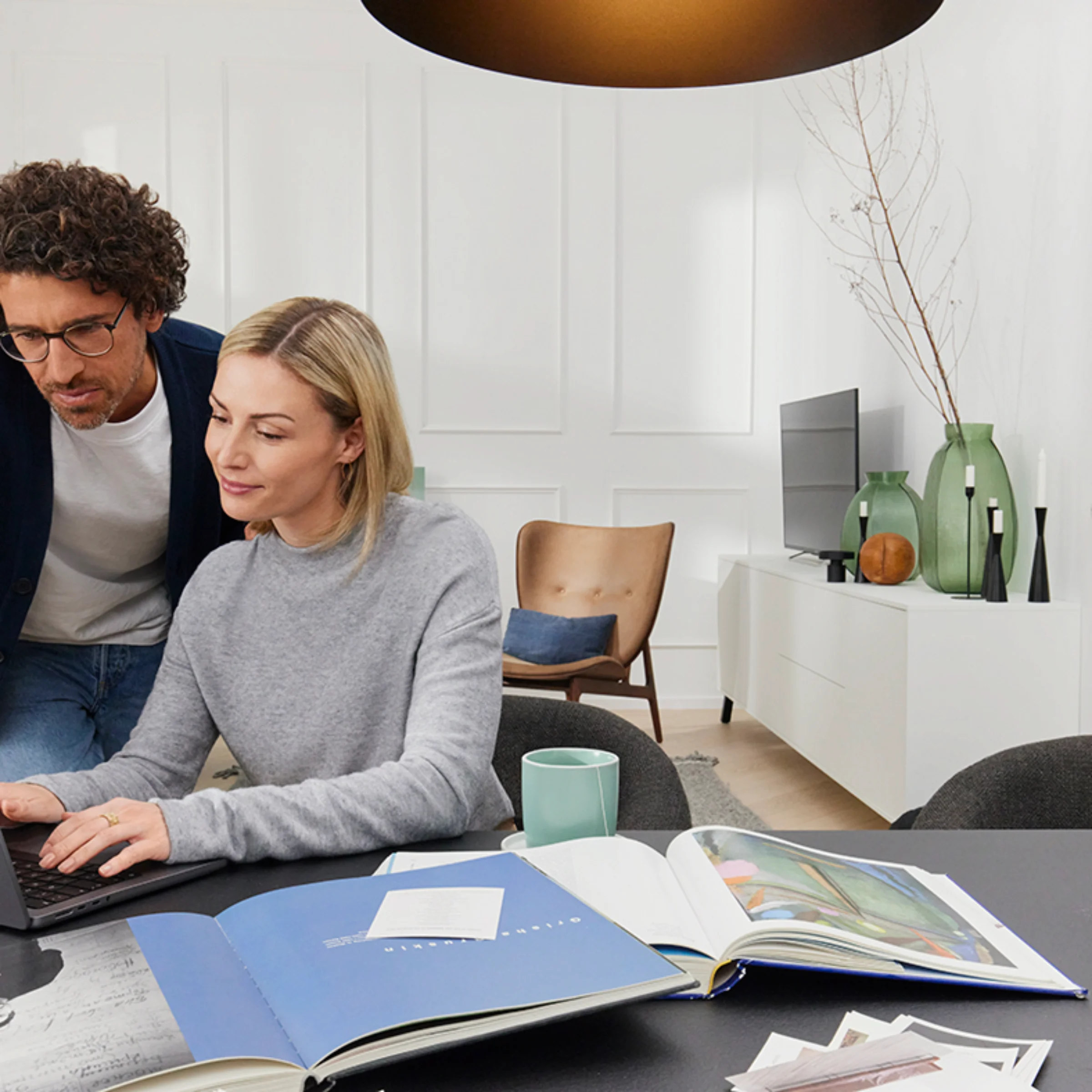 Ein Paar arbeitet gemeinsam an einem Laptop in einem modernen Wohnzimmer mit Nolte Living.