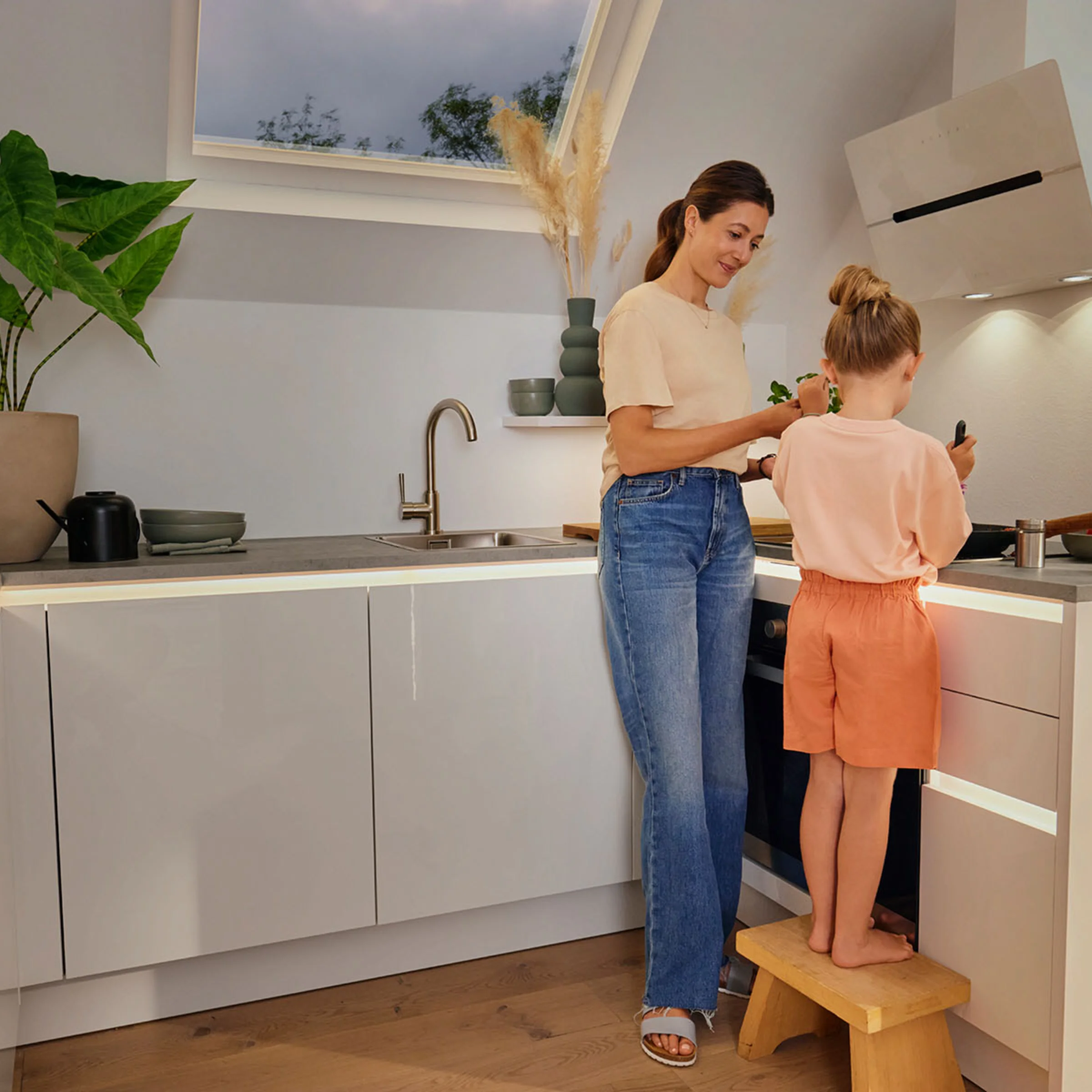 Eine Frau und ein Kind kochen gemeinsam in einer modernen Nolte Küchen-Einbauküche.