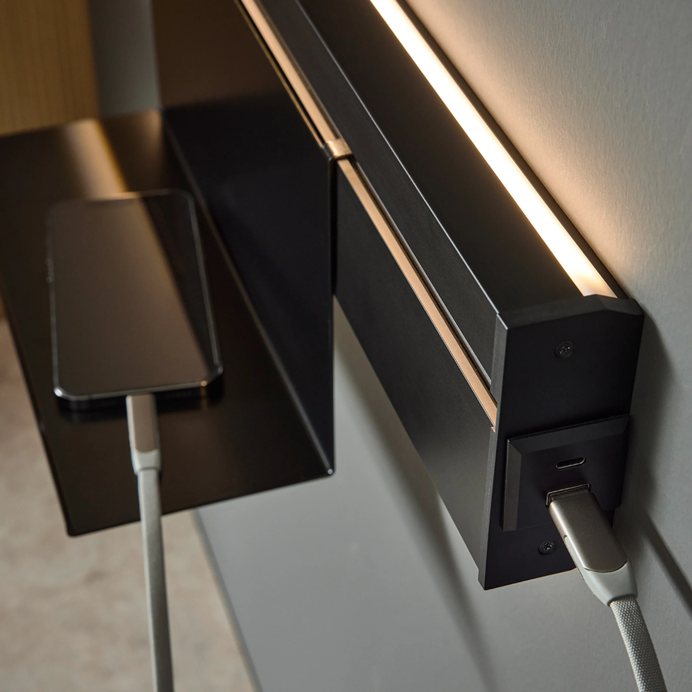 Ein Smartphone lädt auf einem Regal mit integrierter Beleuchtung; modernes Design von Nolte Living.