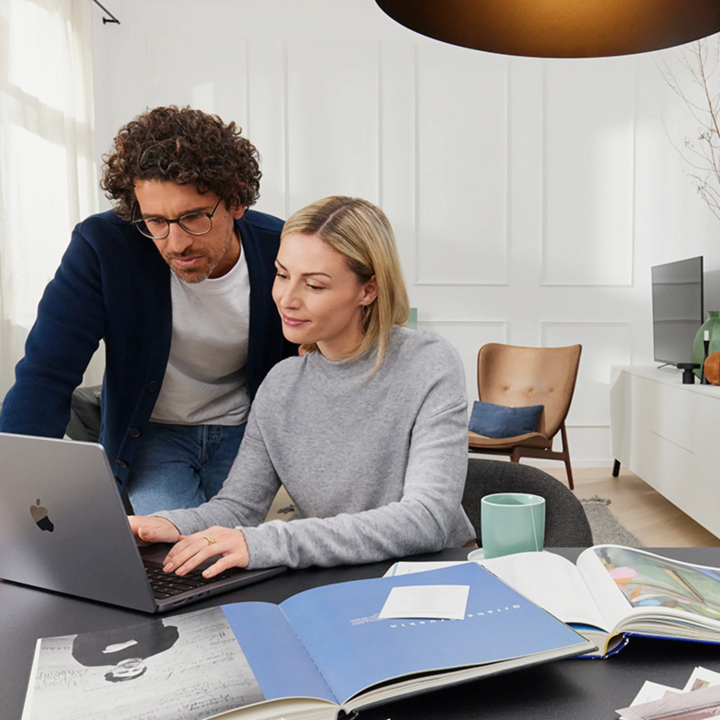 Ein Paar arbeitet an einem Laptop in einem modernen Wohnzimmer mit Nolte Living.