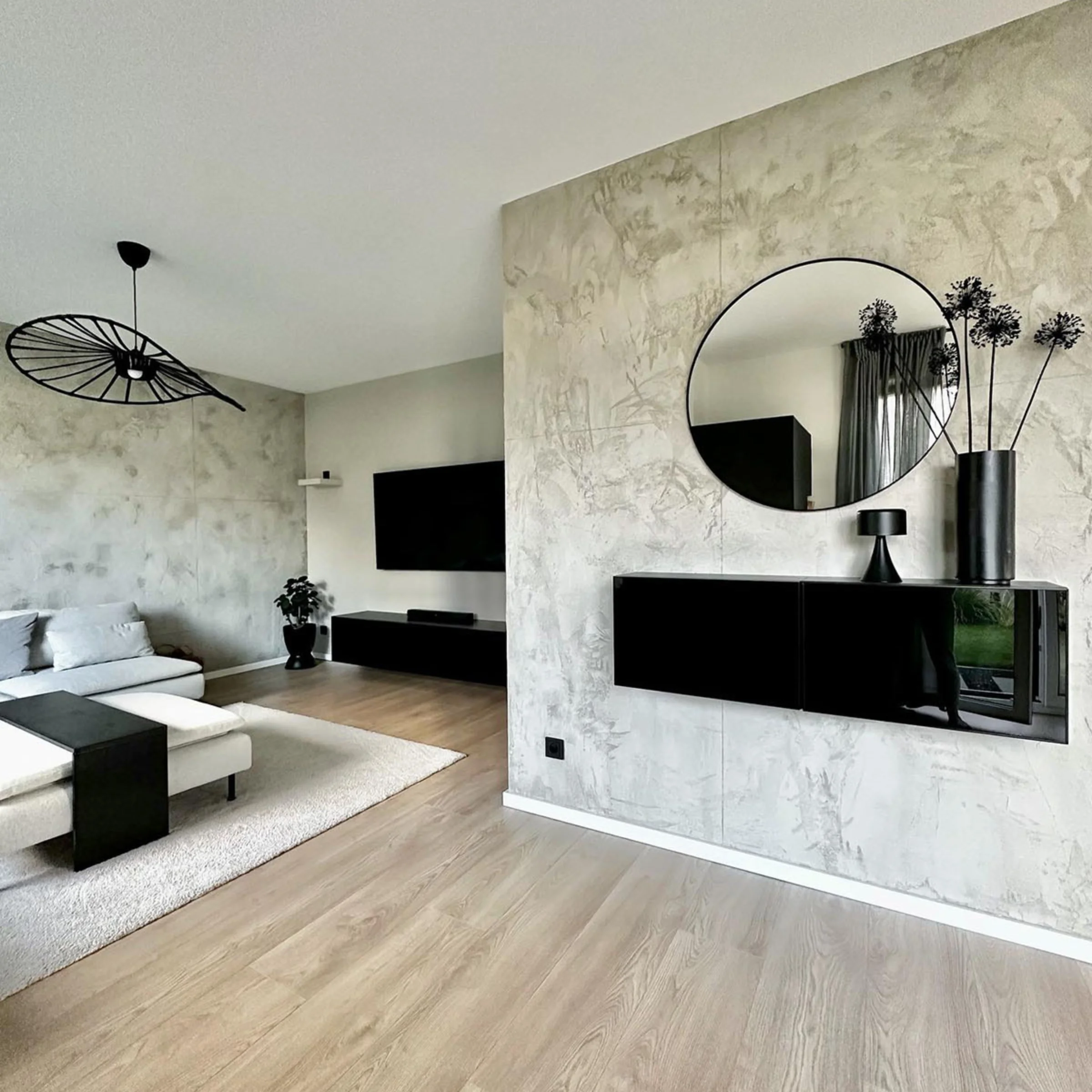 Ein modernes Wohnzimmer mit schwarzem Dekor, Sofa und Fernseher, gestaltet von Nolte Living.