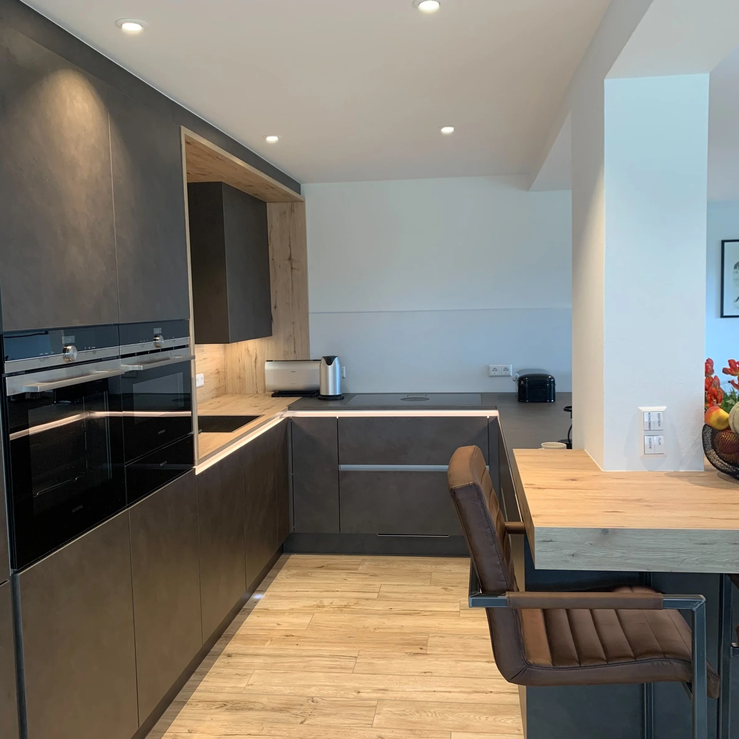 Eine moderne Küche mit dunklen Schränken und Holzakzenten, ausgestattet von Nolte Küchen.