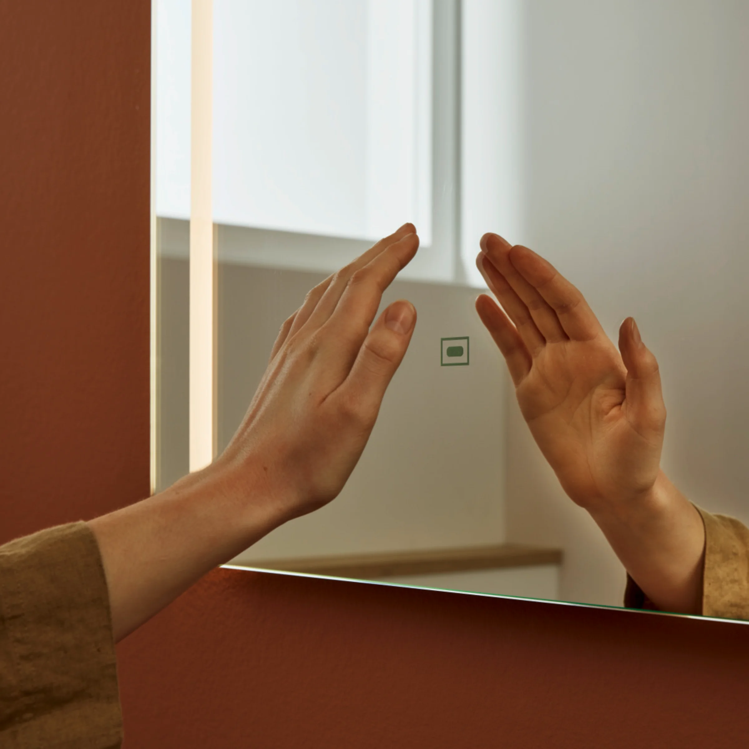 Eine Hand berührt einen beleuchteten Spiegel in einem stilvollen Badezimmer von Nolte SPA.