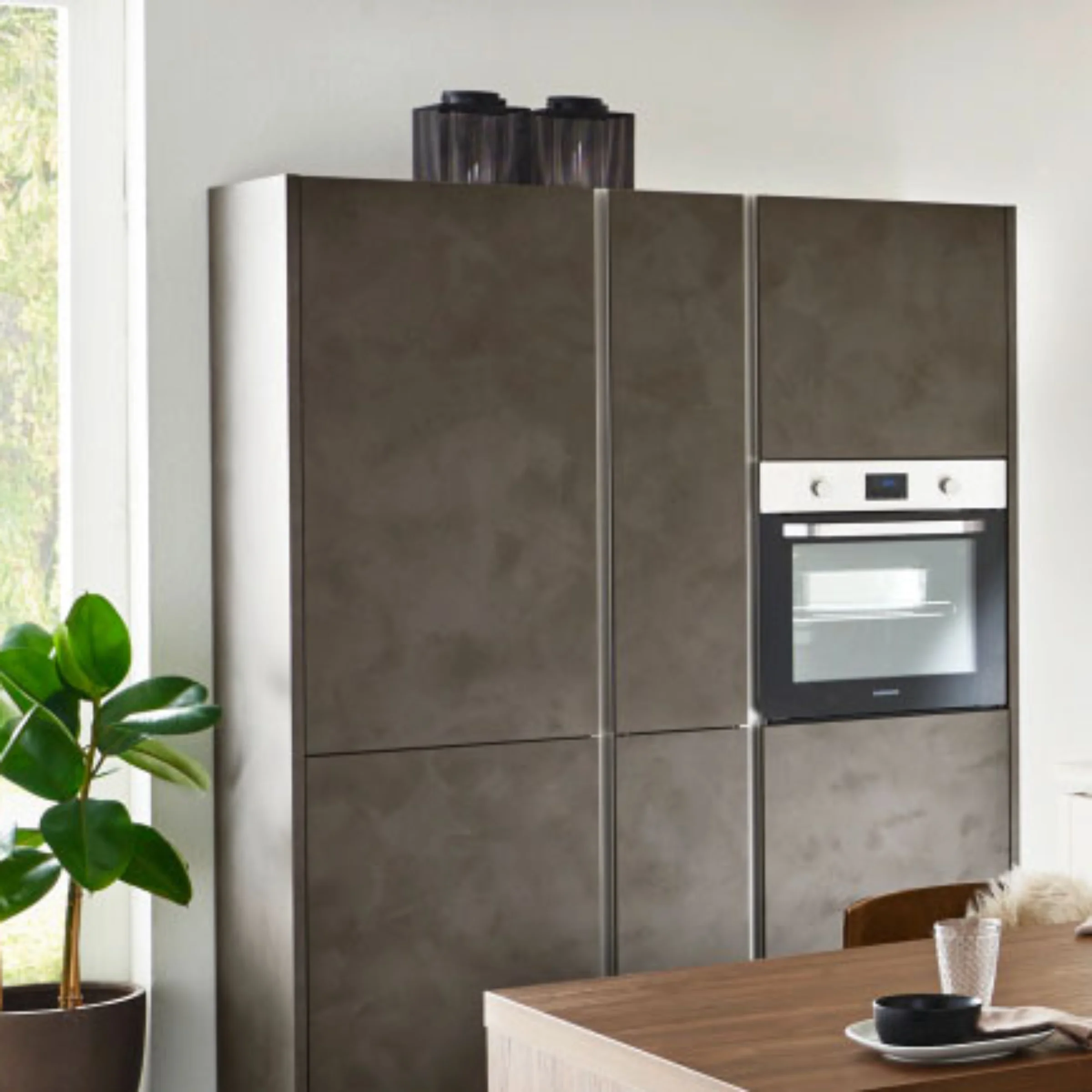 Eine moderne Küche mit grauen Schränken und eingebautem Ofen von Nolte Küchen.