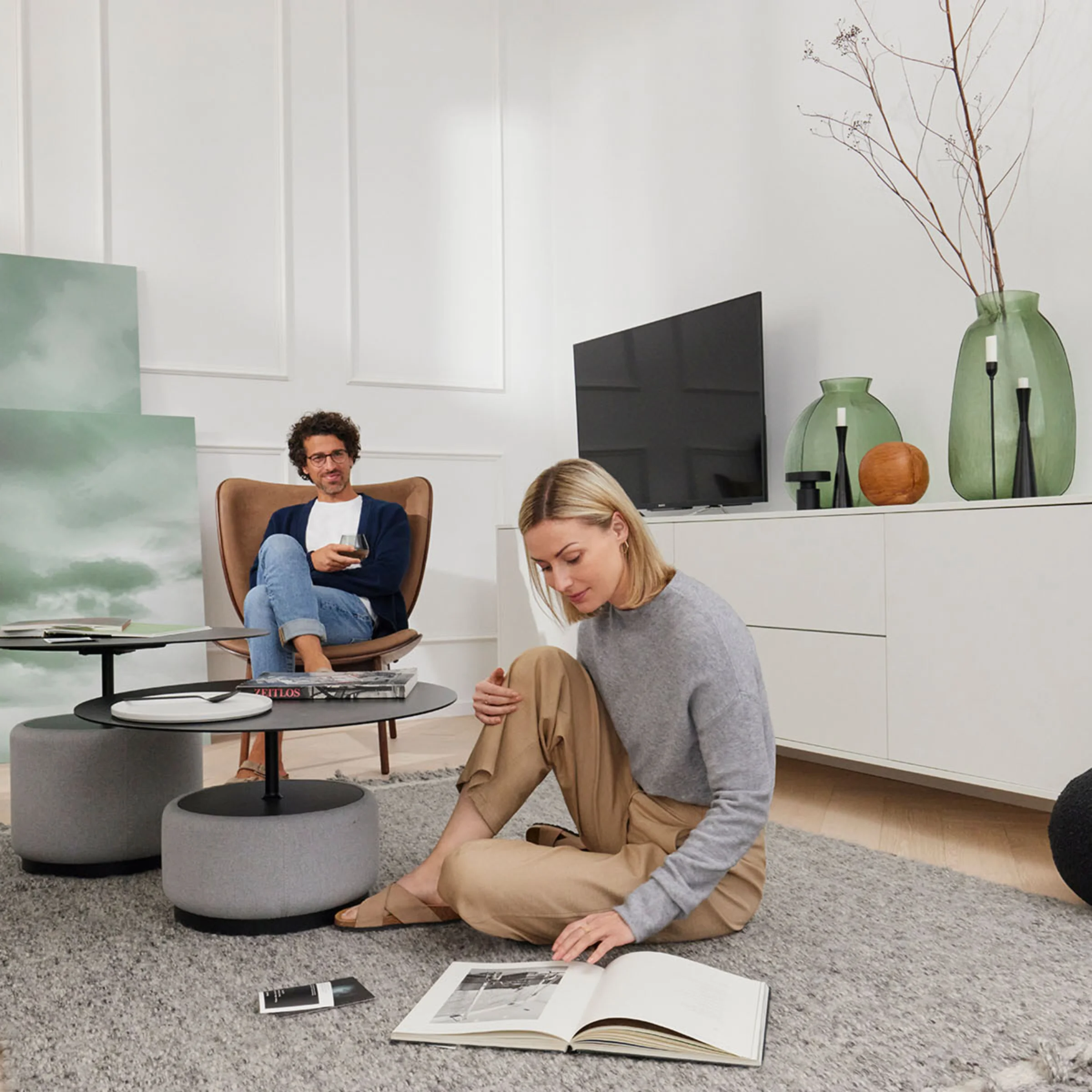 Ein modernes Wohnzimmer mit Nolte Living, in dem zwei Personen lesen und entspannen.