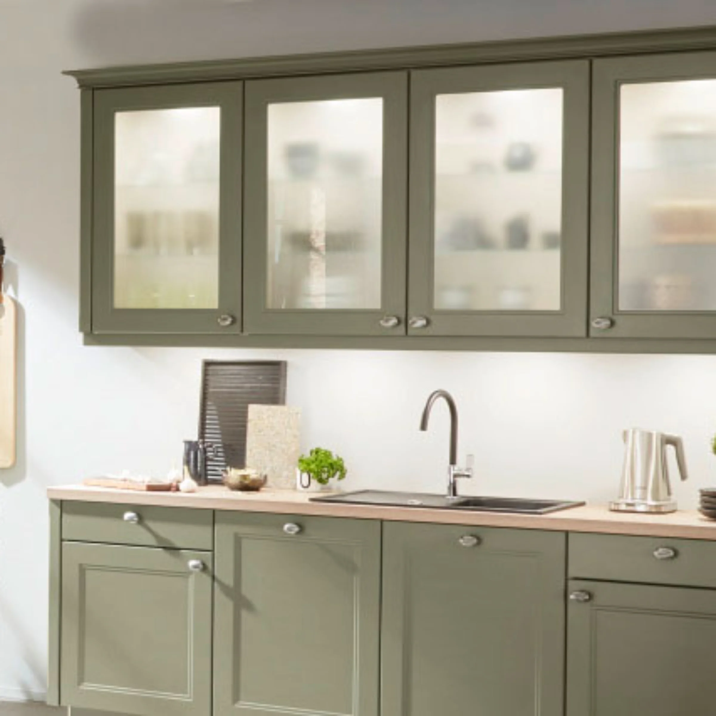 Eine moderne Küche mit grünen Schränken und Dekorationen. Nolte Küchen.