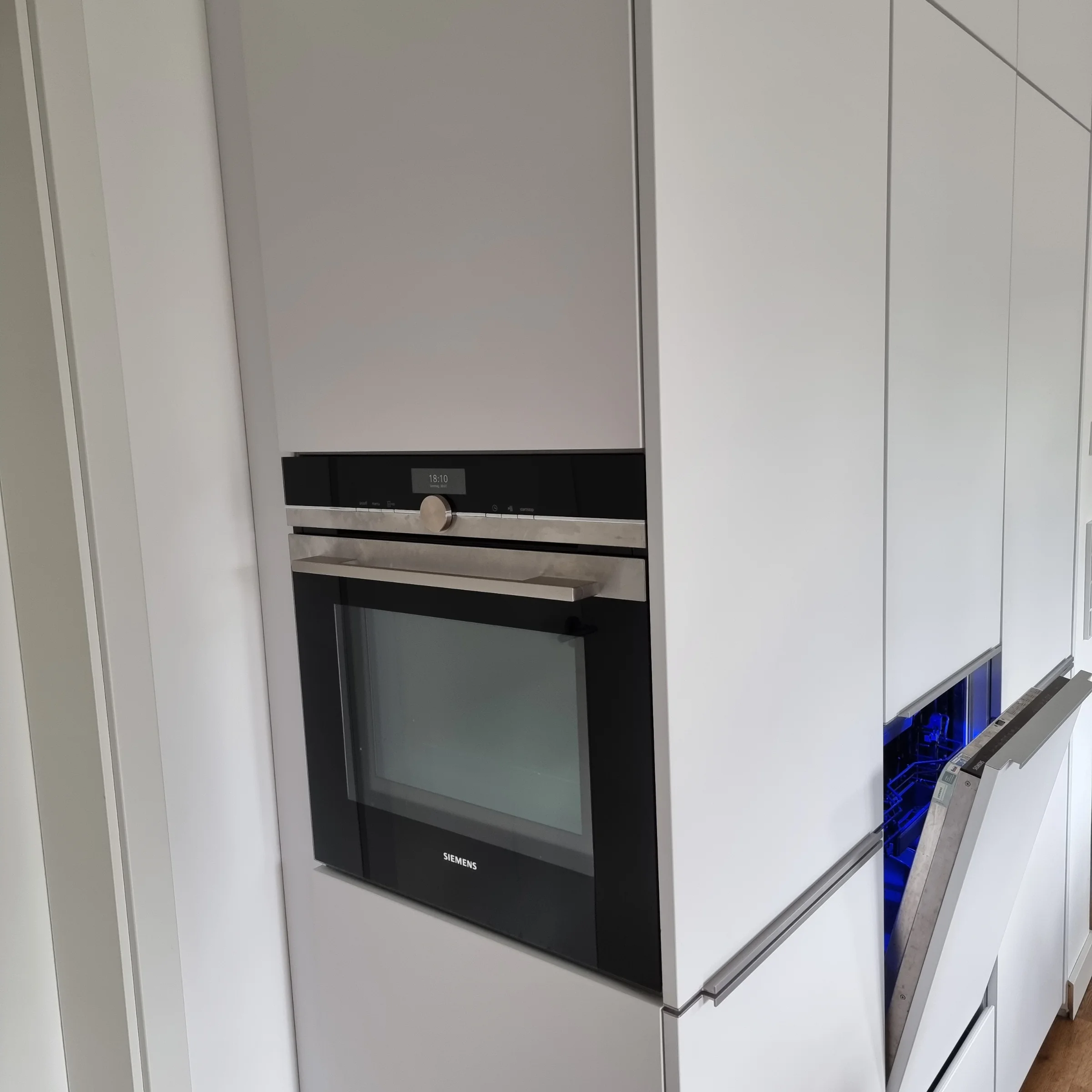 A modern built-in kitchen with white cabinets and an integrated oven by Nolte Kitchen.