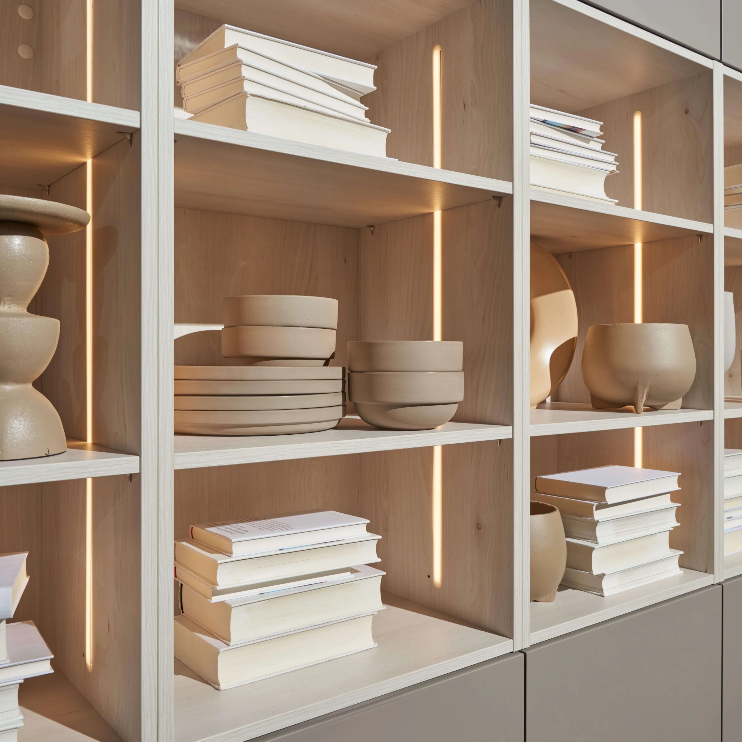 Regal mit dekorativen Schalen und Büchern, elegant inszeniert mit Beleuchtung, Teil von Nolte Living.