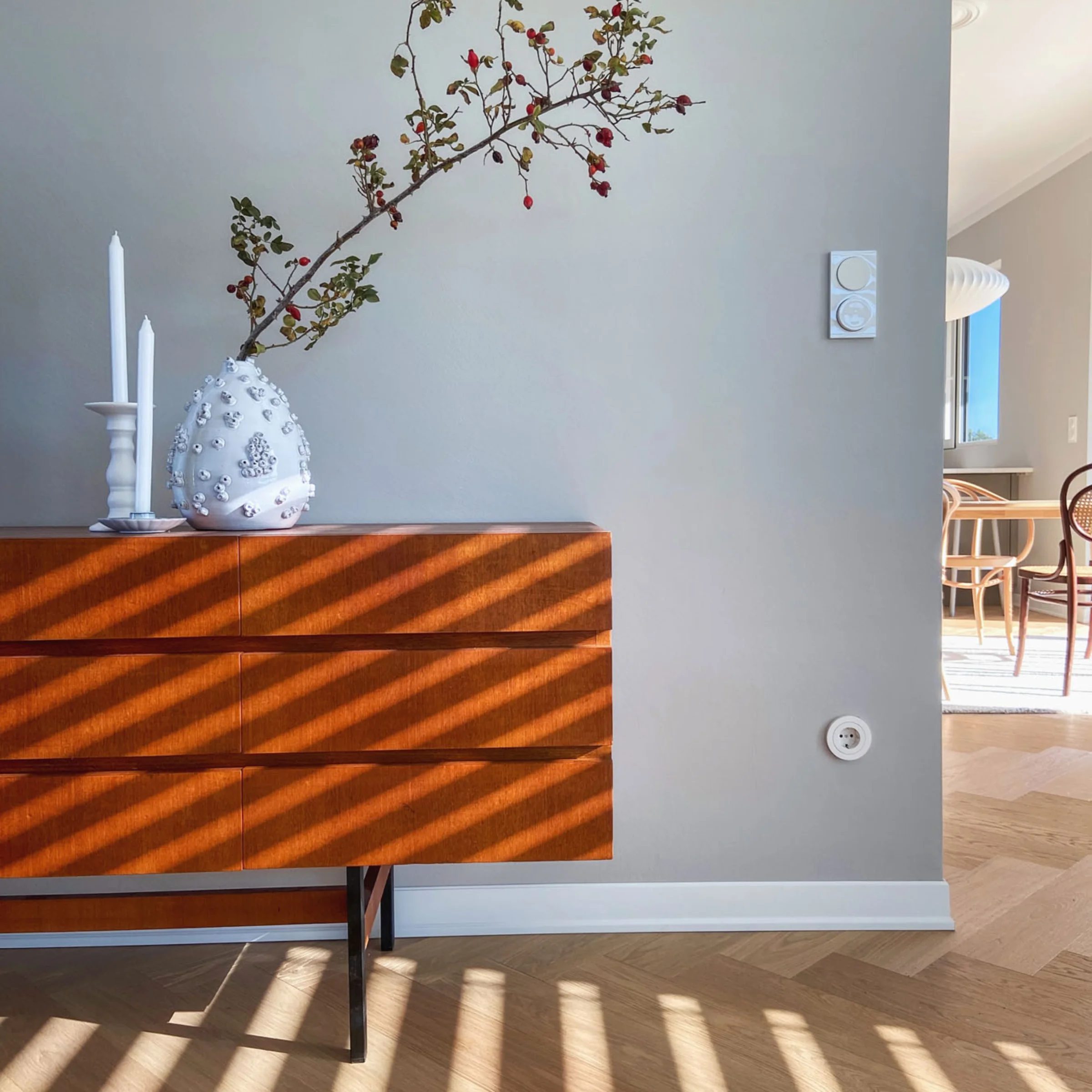 Ein Sideboard mit Vase und Kerzen in einem lichtdurchfluteten Raum, Nolte Living.