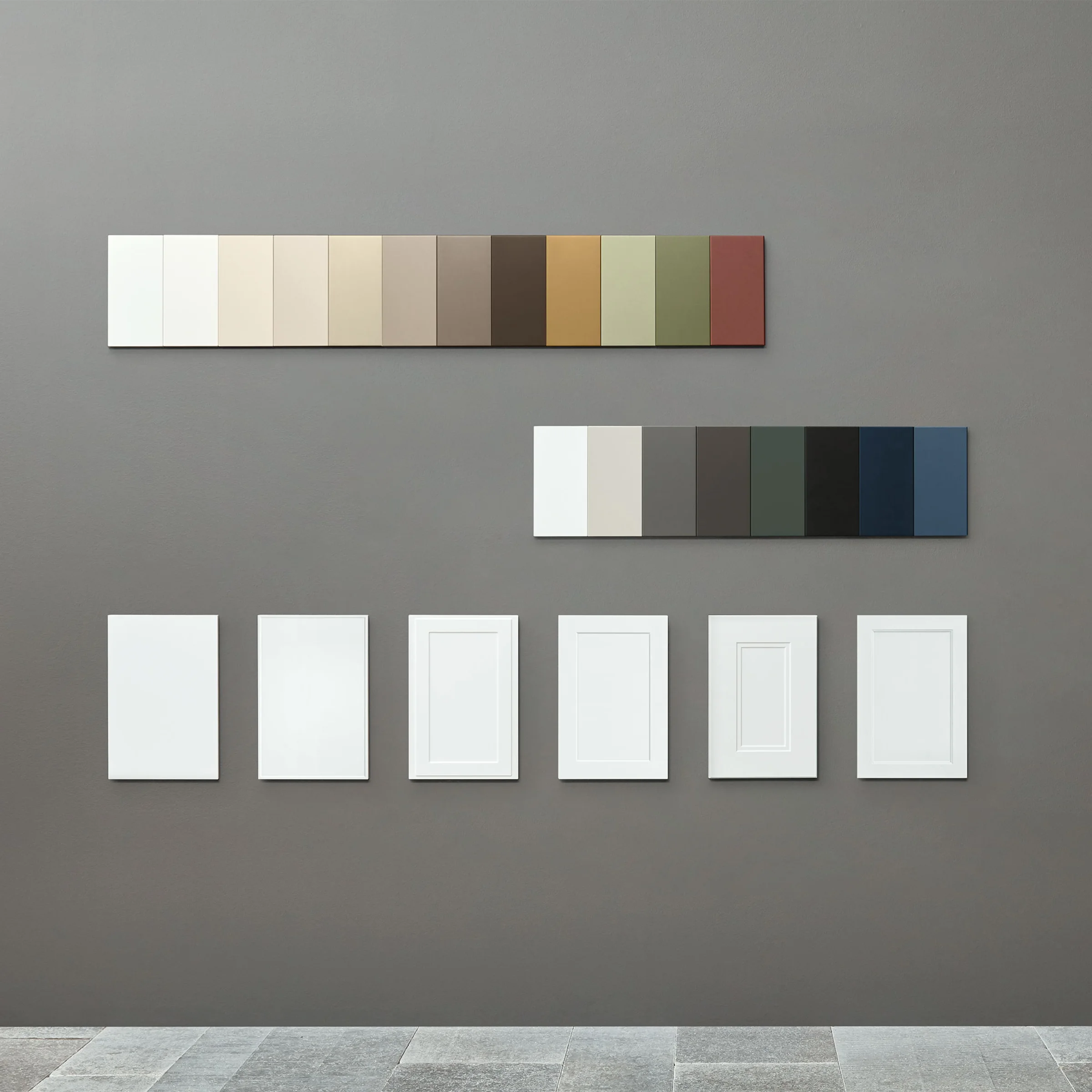 Farbmuster und Rahmen sind an einer grauen Wand ausgestellt, passend zu Nolte Living.