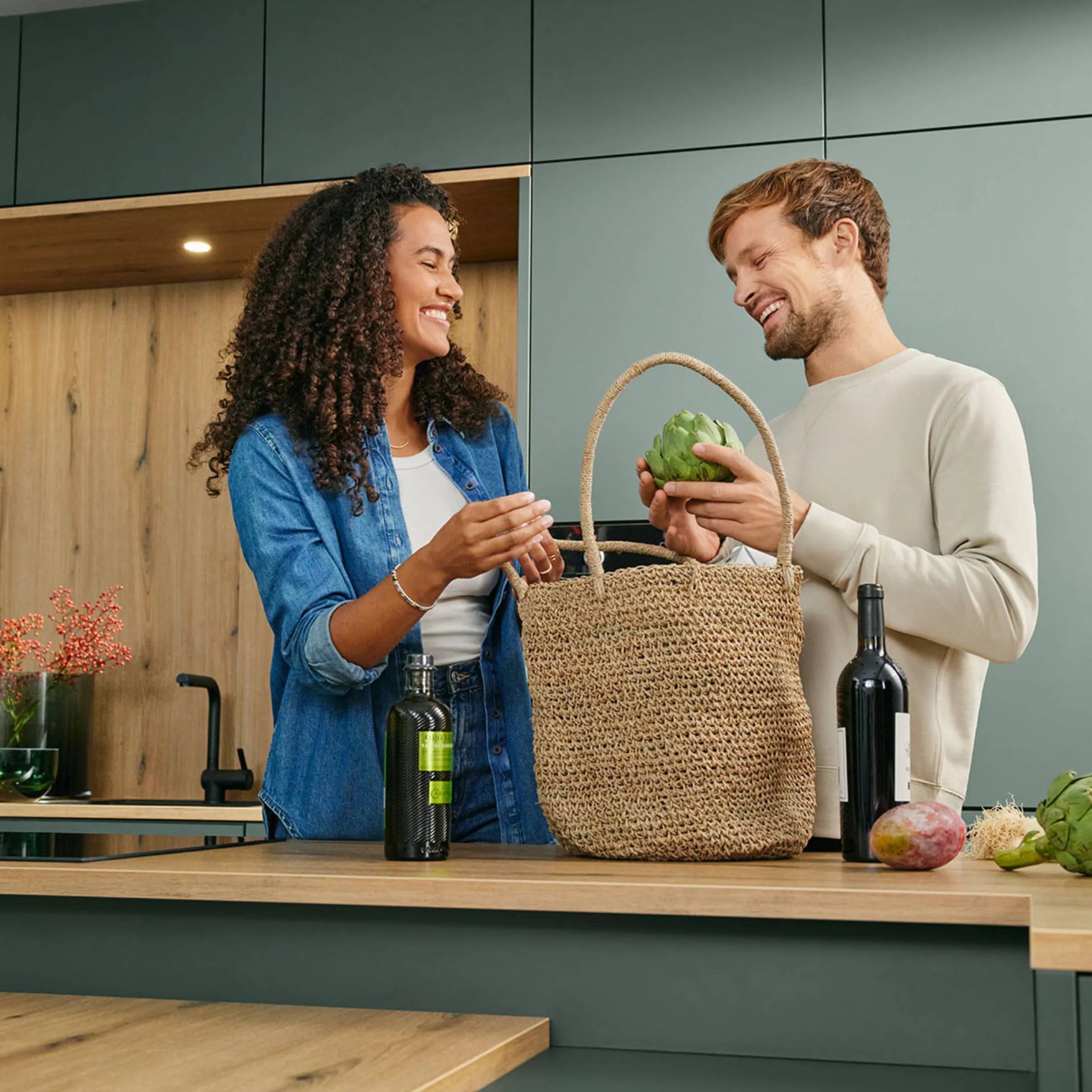 A couple unpacks vegetables in a modern Nolte kitchen setting.