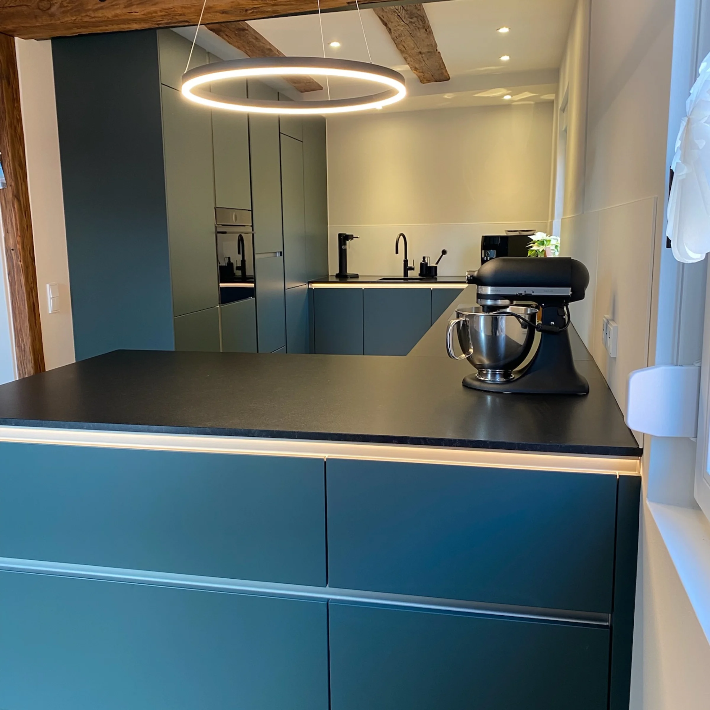 Eine moderne Küche mit schwarzen Oberflächen und Holzbalken, Nolte Küchen.