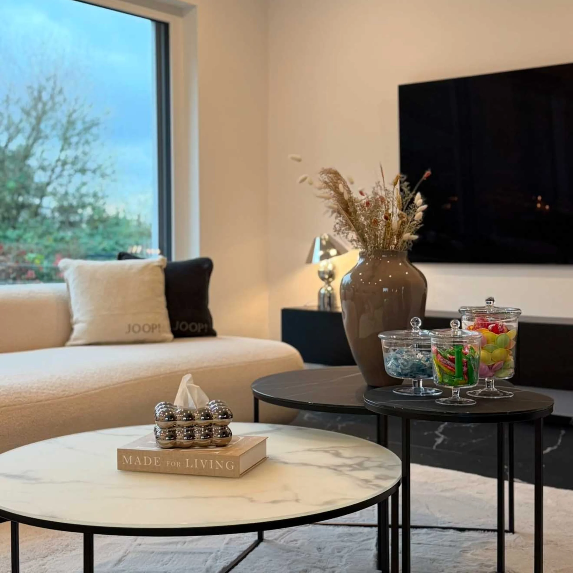 Ein stilvoll eingerichtetes Wohnzimmer mit Couchtischen und Dekorationen, präsentiert von Nolte Living.