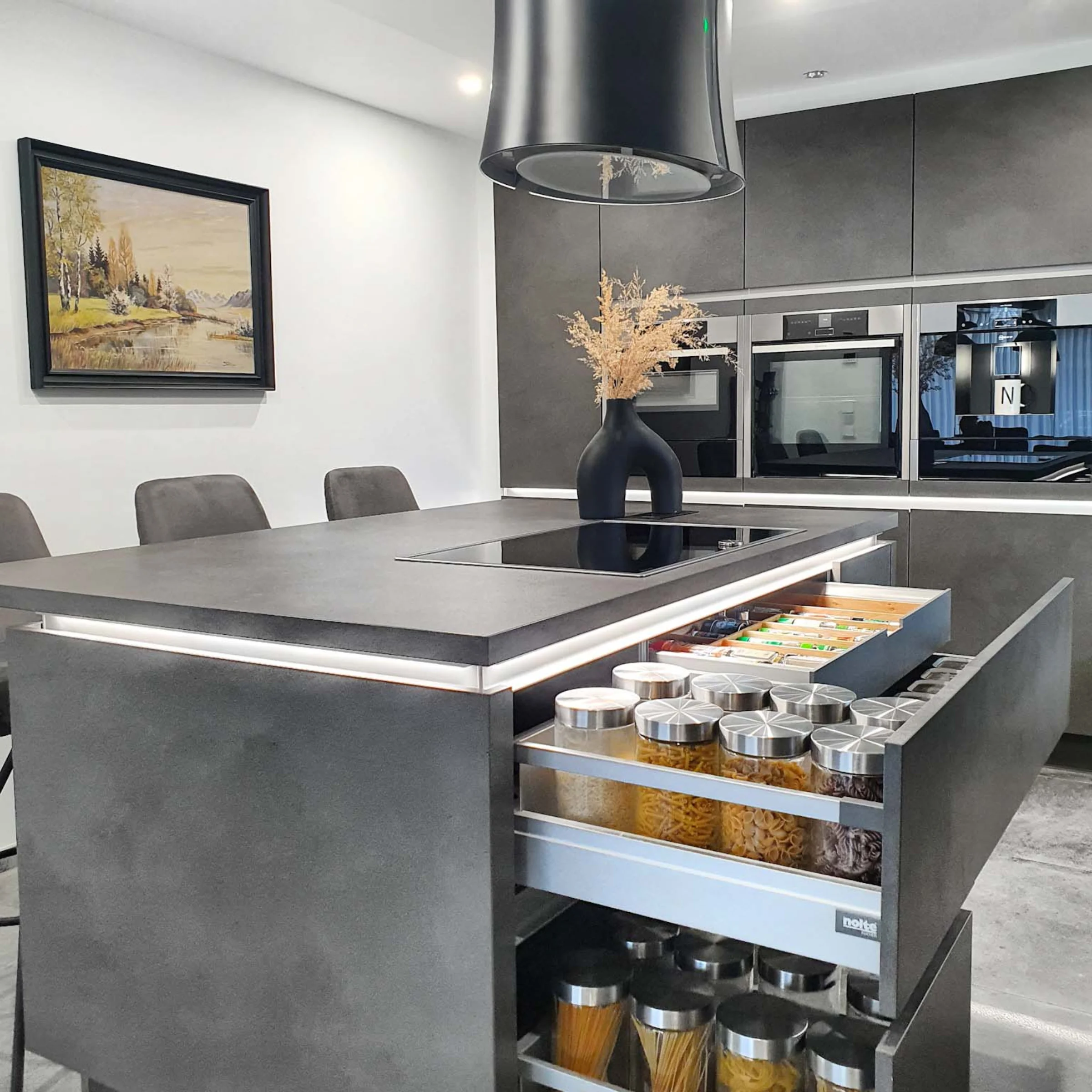 Eine moderne Küche mit grauen Schränken und einer Kochinsel, gestaltet von Nolte Küchen.