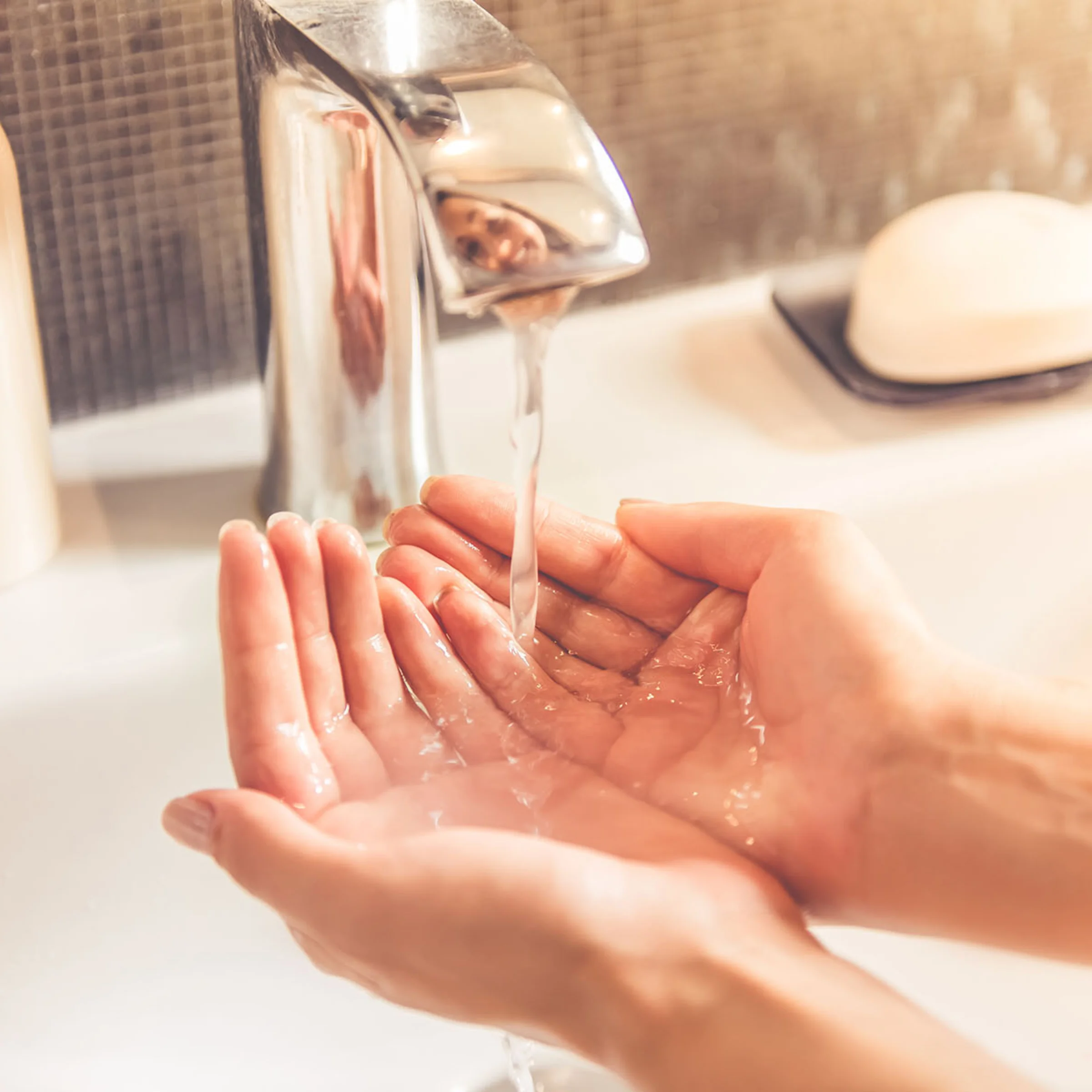 Eine Person hält ihre Hände unter fließendes Wasser im Badezimmer, Nolte SPA.