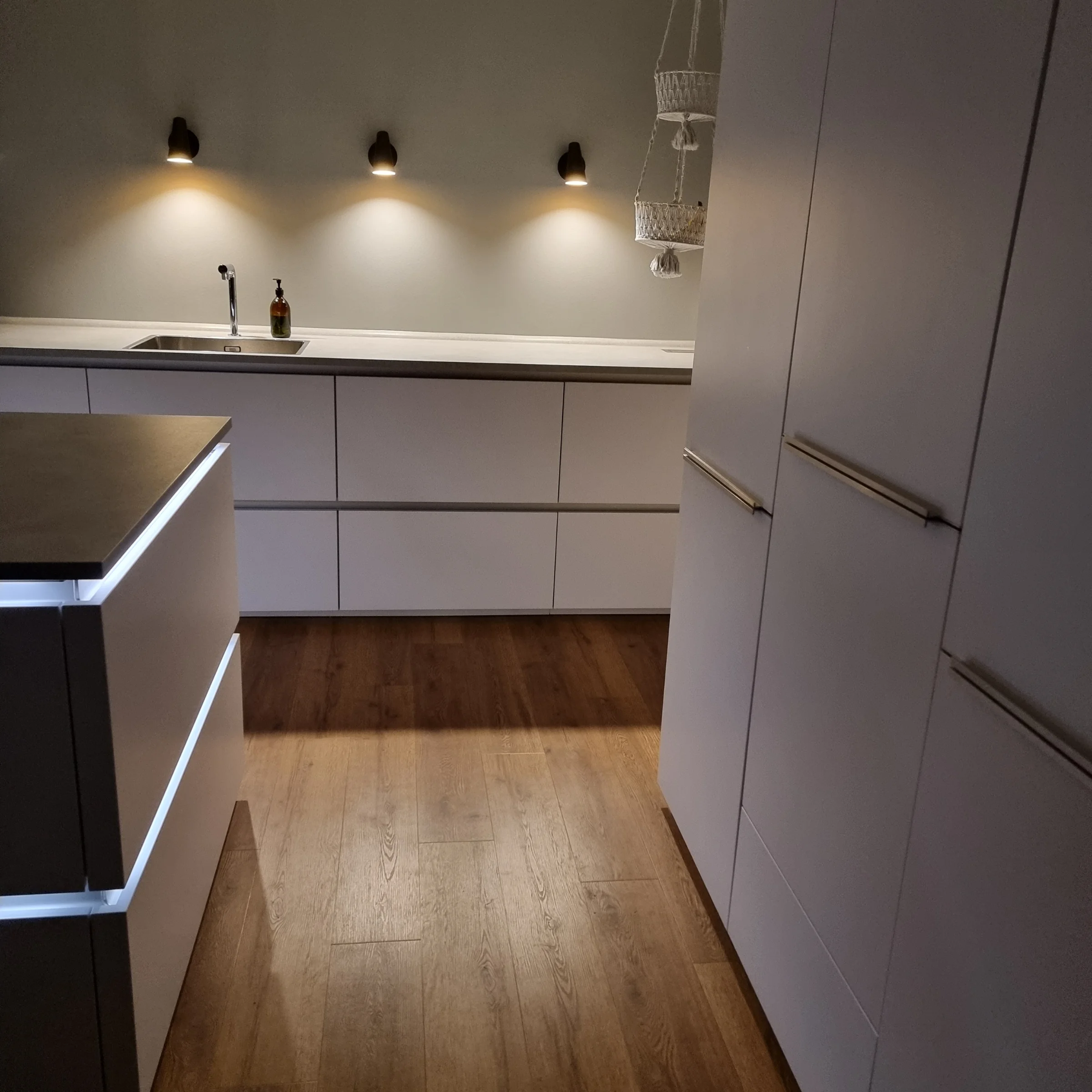 A modern kitchen with wooden floors and illuminated cabinets by Nolte Kitchen.