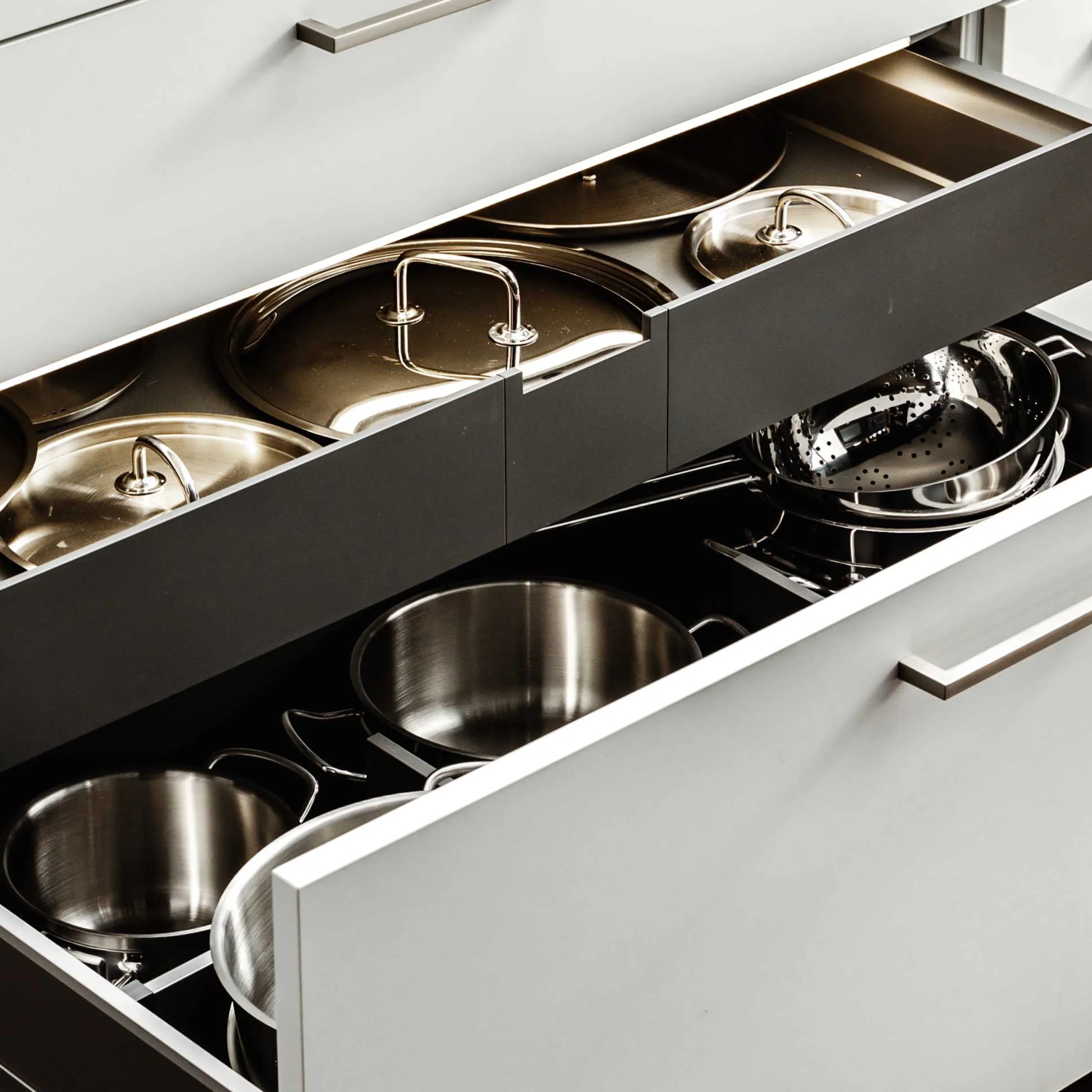 Ein geöffneter Küchenschrank zeigt Töpfe und Pfannen in einem modernen Design von Nolte Küchen.