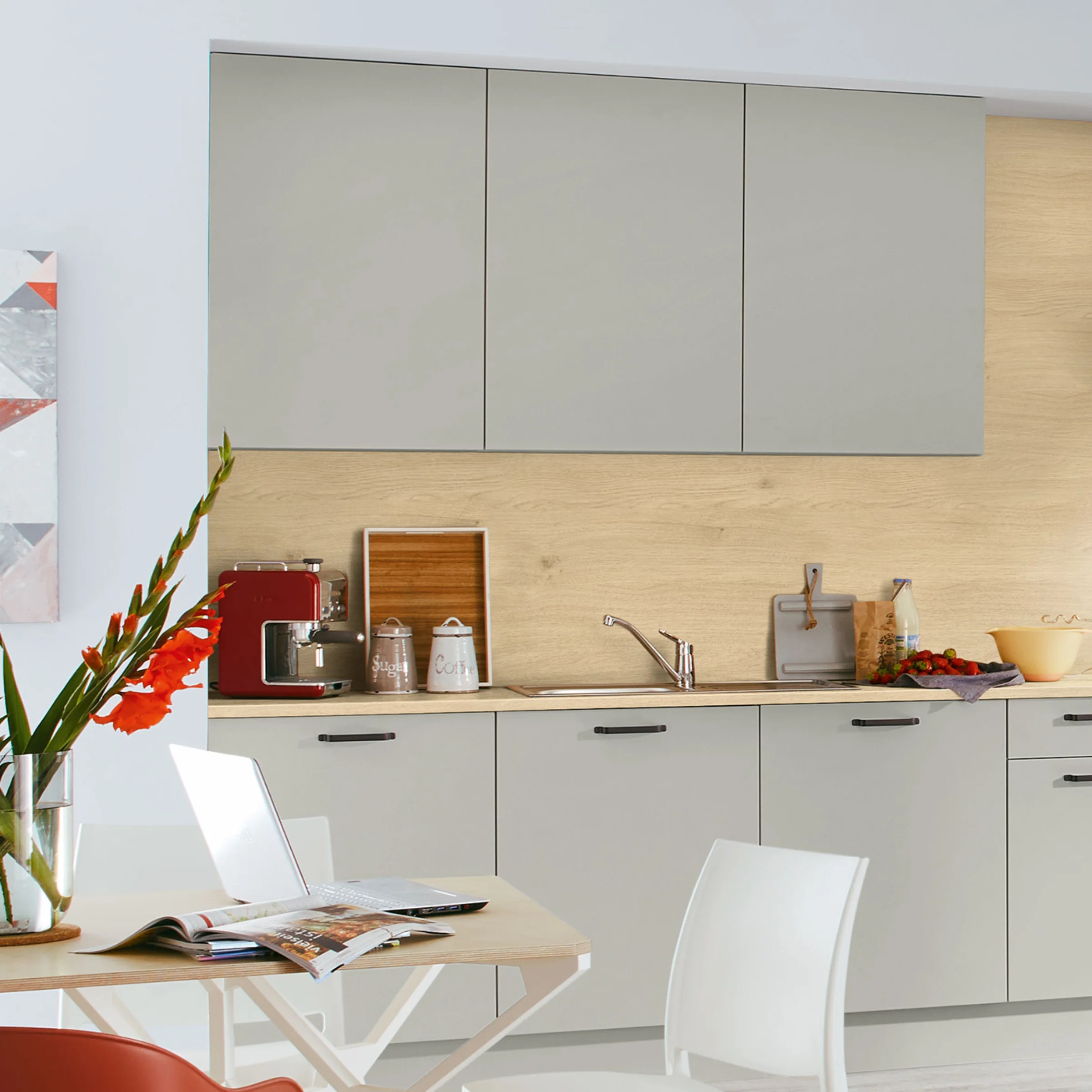 In einer modernen Küche mit grauen Schränken und Holzdetails steht ein Tisch mit Blumen. Nolte Küchen.