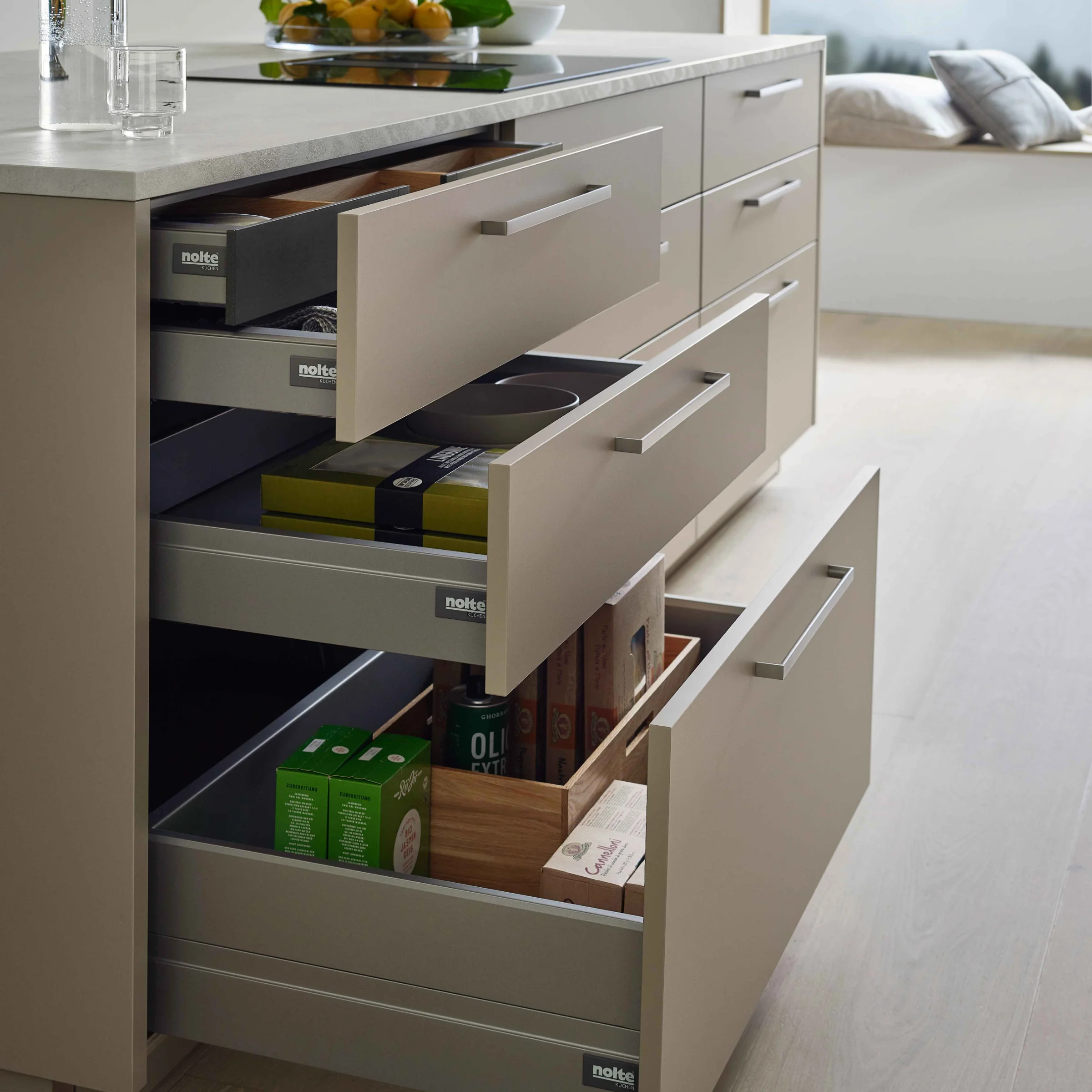Eine moderne Küche mit offenen Schubladen und einem Kochfeld auf der Insel, Nolte Küchen.