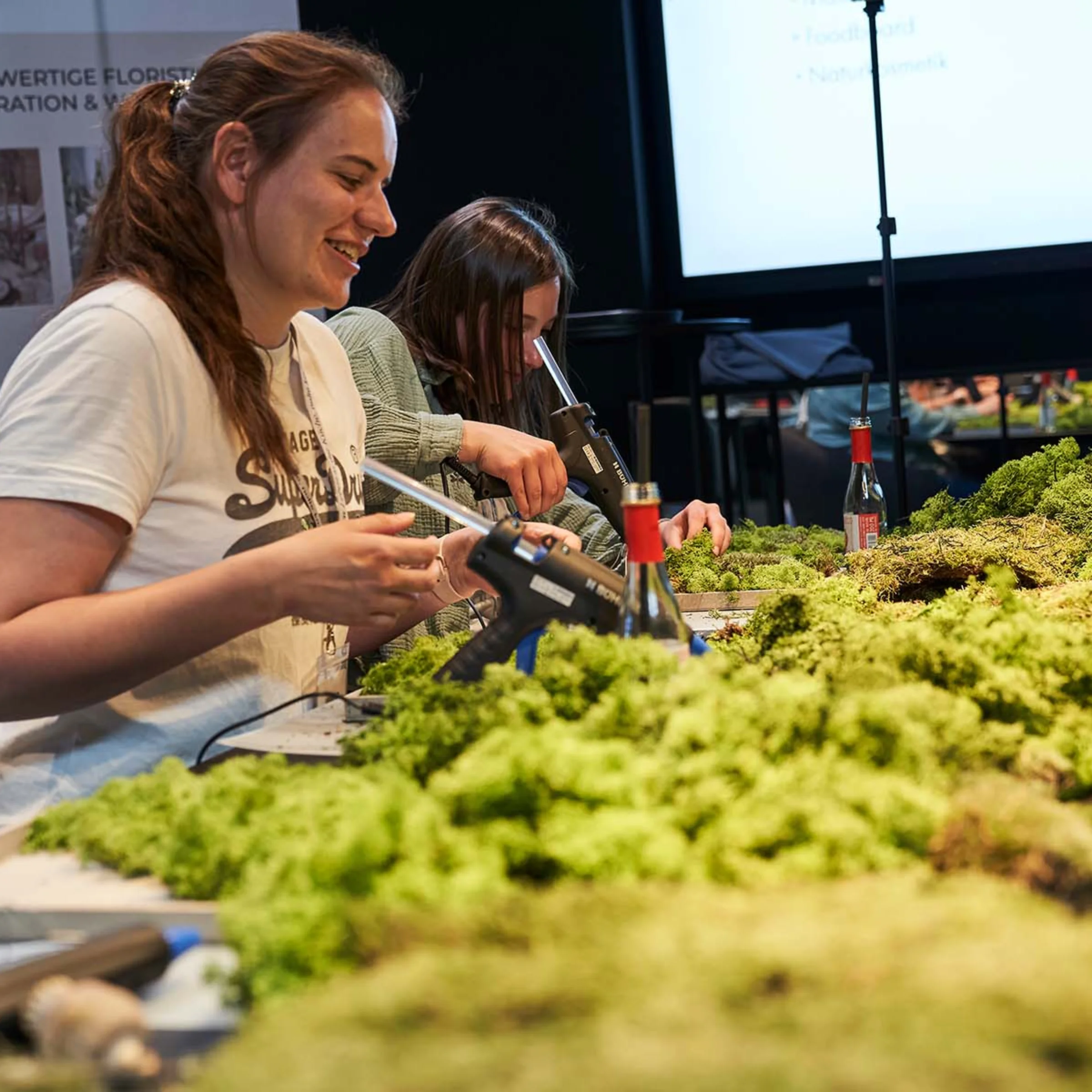 Two people creatively working on a moss project in a modern room.