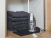 Ein Bügeleisen neben schwarzen Handtüchern in einem Schrank integriert, ideal für Nolte Hauswirtschaftsräume.