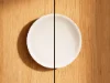 Ein weißer Teller hängt an einer Holzwand als dekoratives Element.