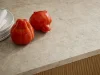 Two red bell peppers and a plate on a countertop in a Nolte kitchen setting.