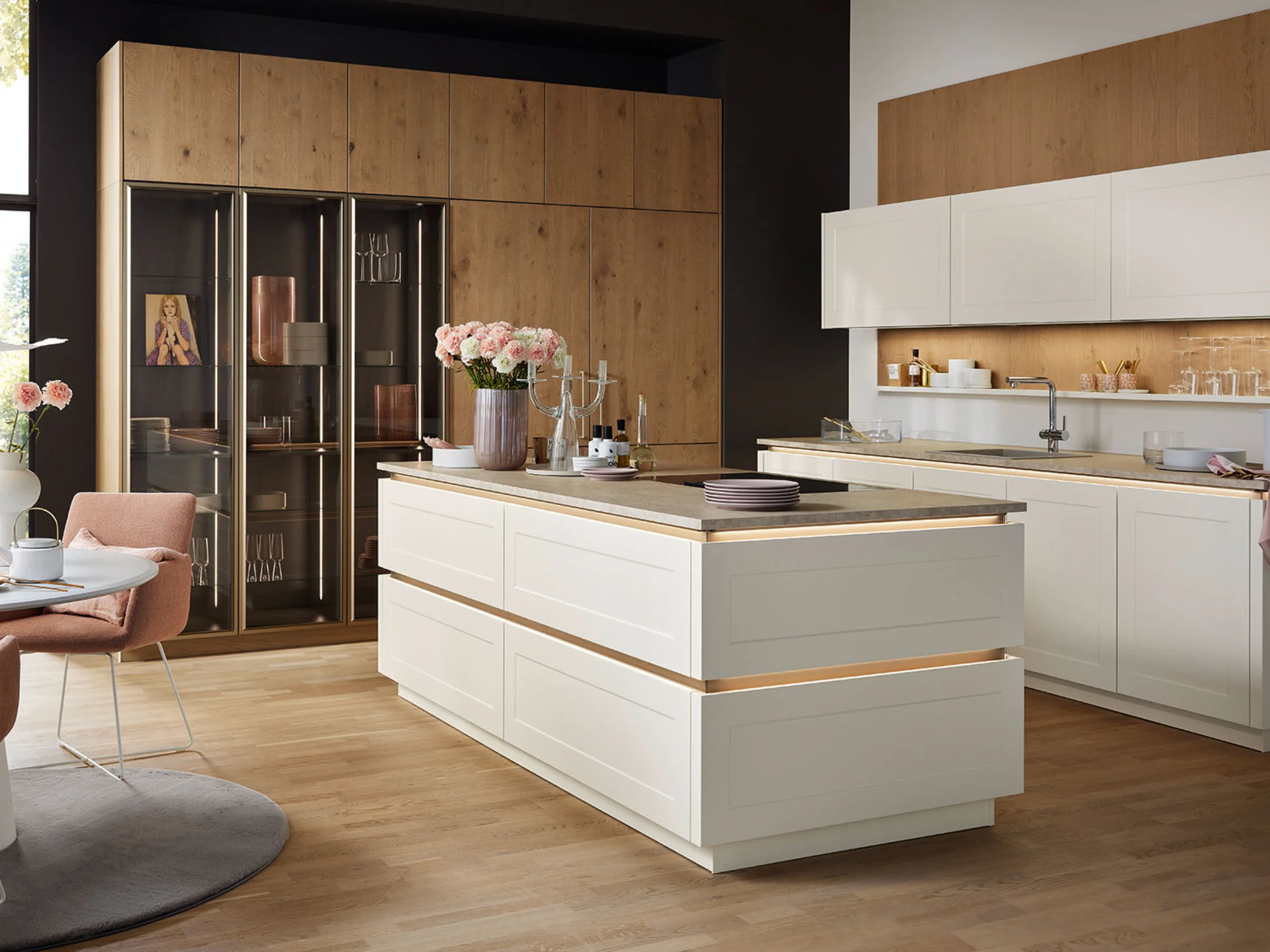 Eine moderne Küche mit Insel und Holzdetails, dekoriert mit Blumen. Nolte Küchen.