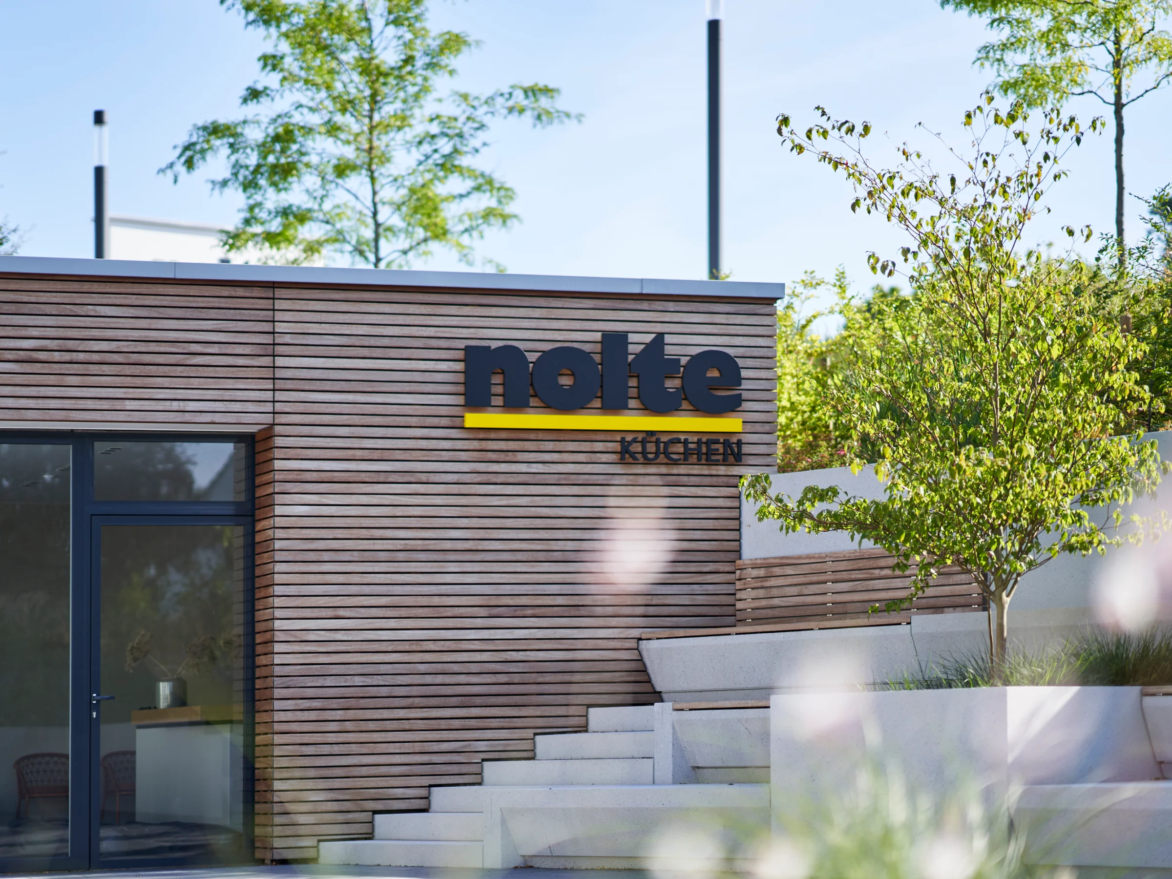 Ein modernes Gebäude mit Holzfassade und dem Logo von Nolte Küchen.