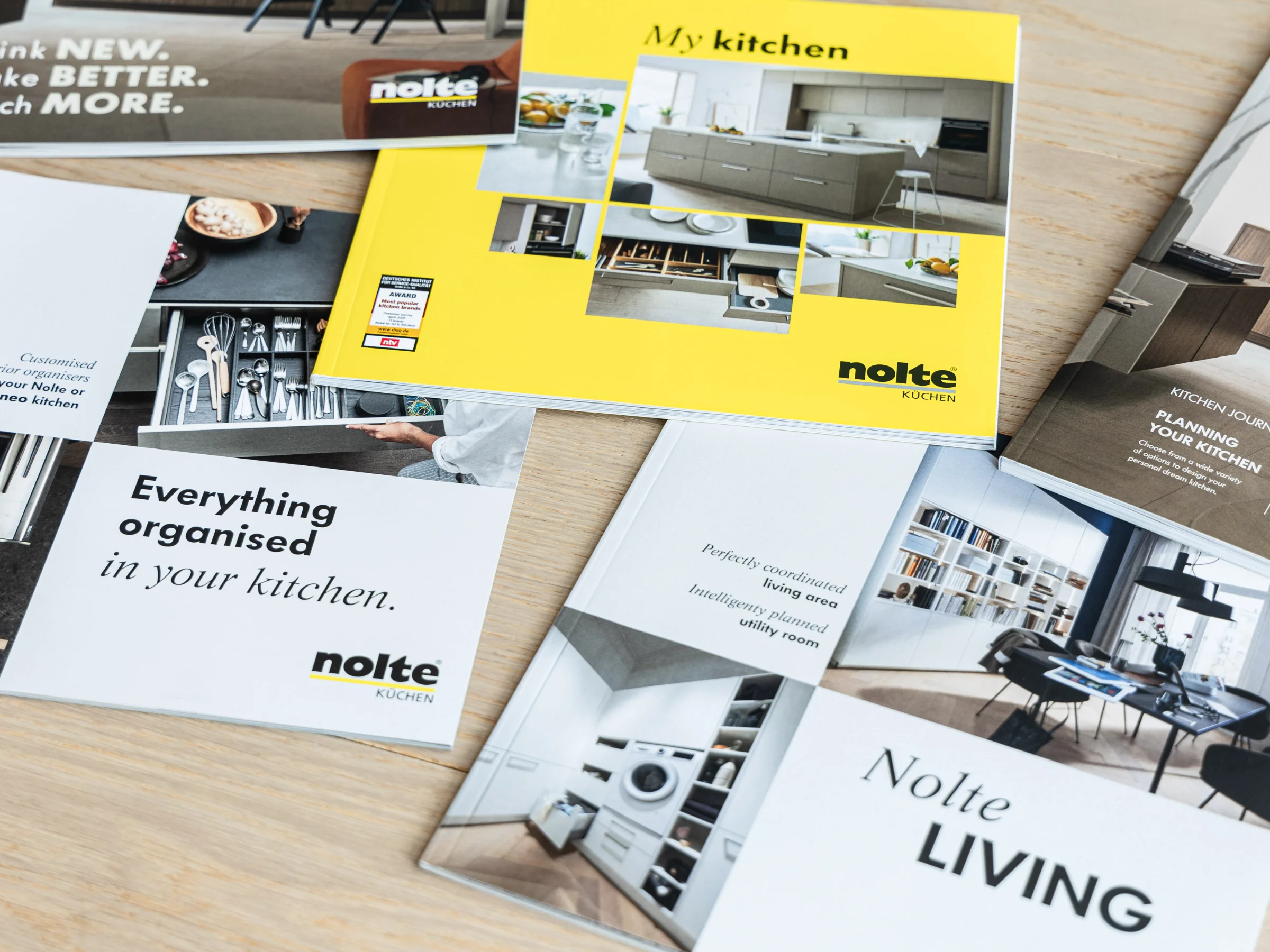 Four brochures on Nolte Kitchens, Nolte Living, and NolteNeo designs are on a table.