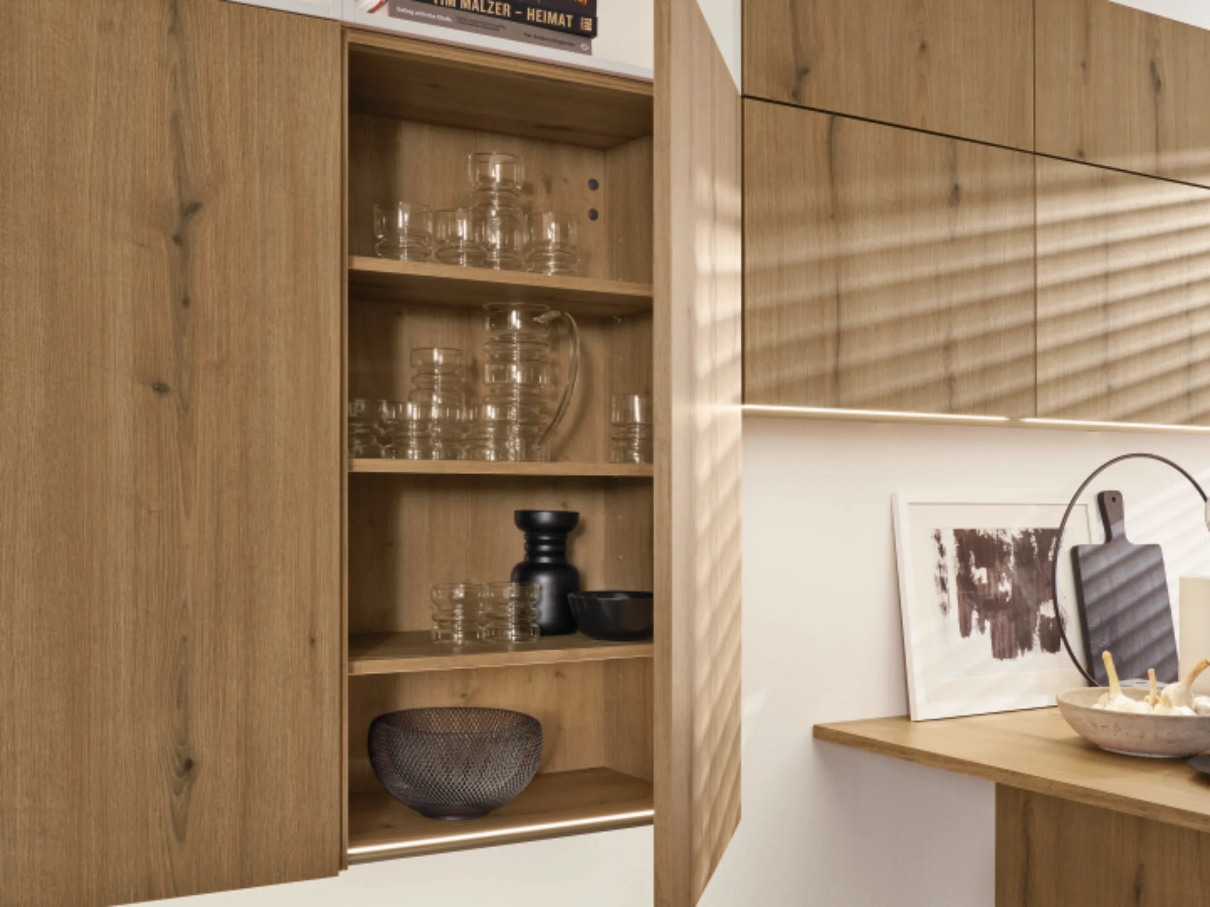 A modern kitchen with wooden cabinets and open shelves, designed by Nolte Kitchen.