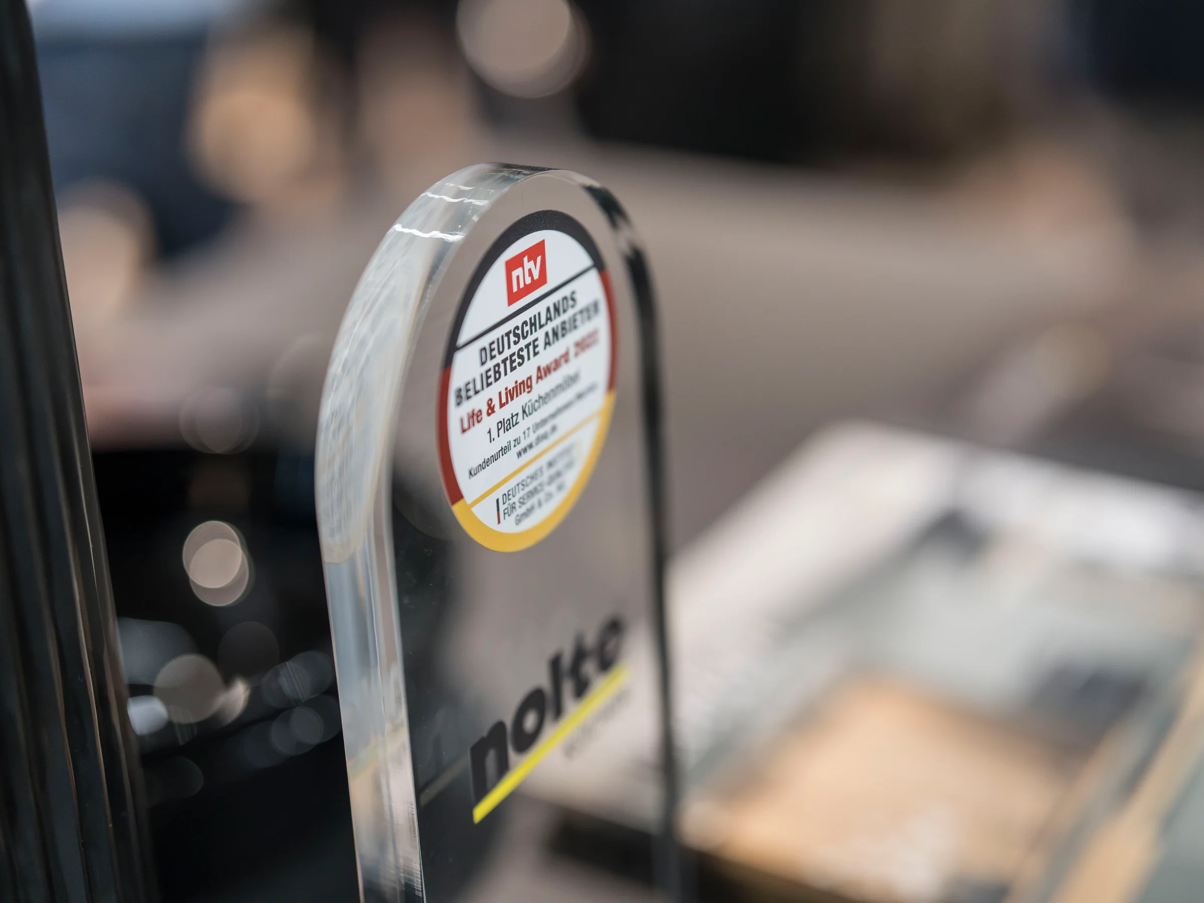Eine gläserne Auszeichnung mit dem Logo von Nolte steht auf einem Tisch.