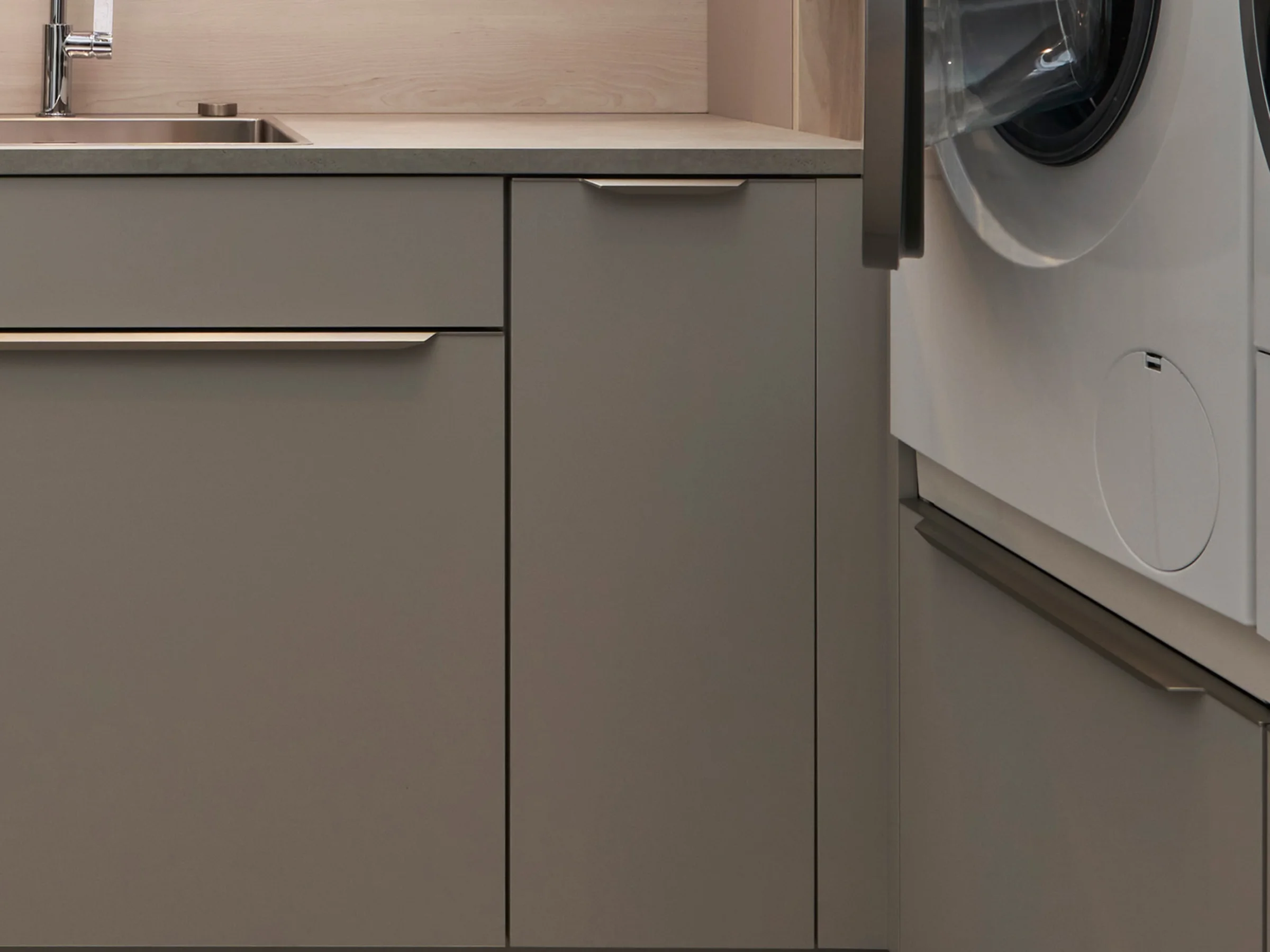 Ein moderner Hauswirtschaftsraum mit grauen Schränken und Waschmaschine, Nolte Hauswirtschaftsräume.