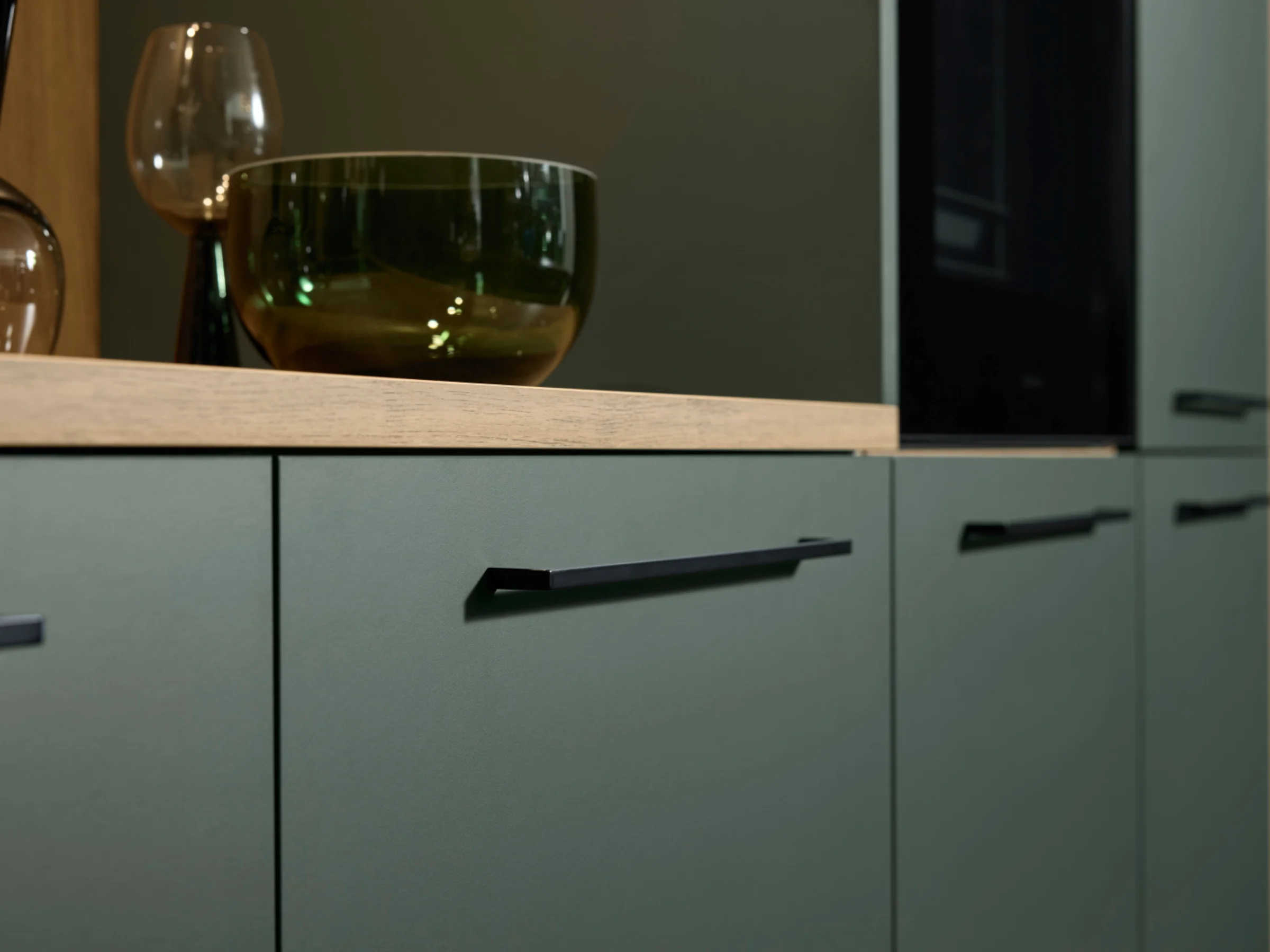 Modern kitchen cabinets with green fronts and black handles by Nolte Kitchen.