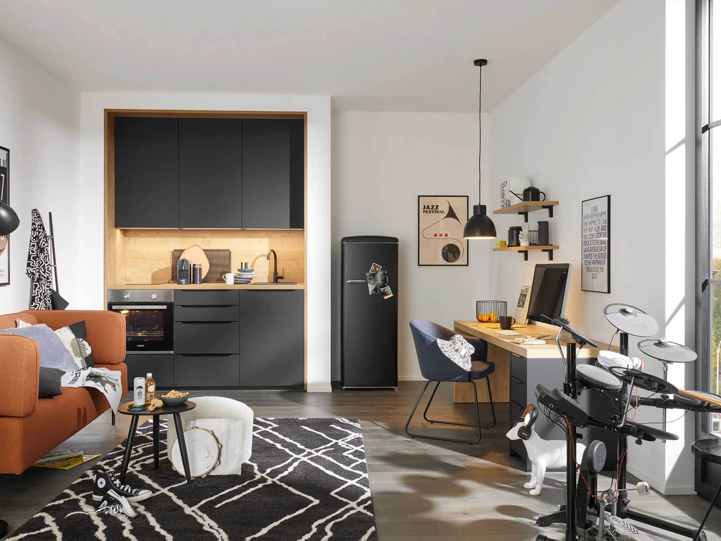 Eine moderne Küche mit schwarzen Schränken und einem gemütlichen Wohnbereich von Nolte Küchen.