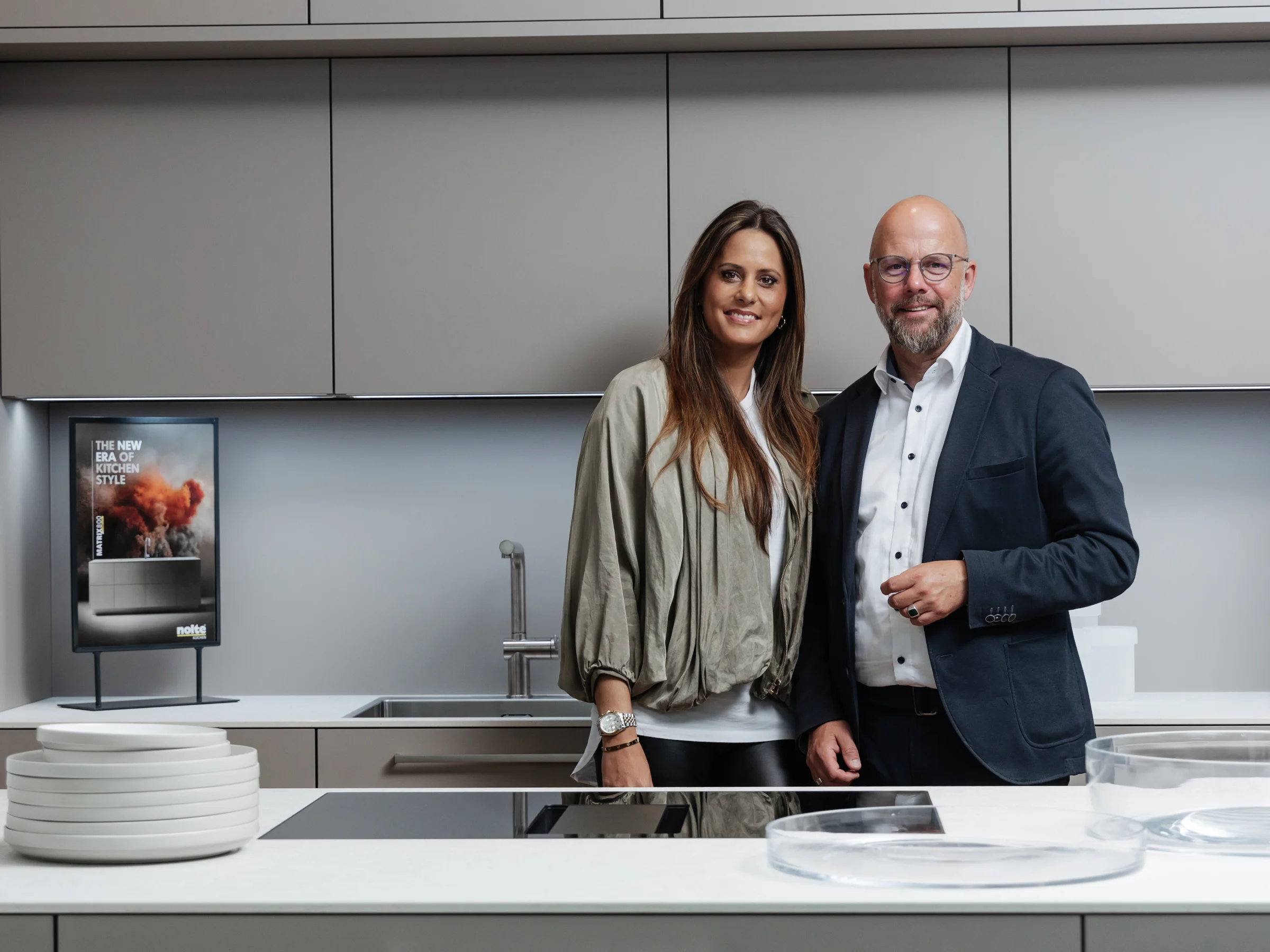 Ein Paar steht in einer modernen Küche mit Insel und integriertem Nolte Küchen Design.