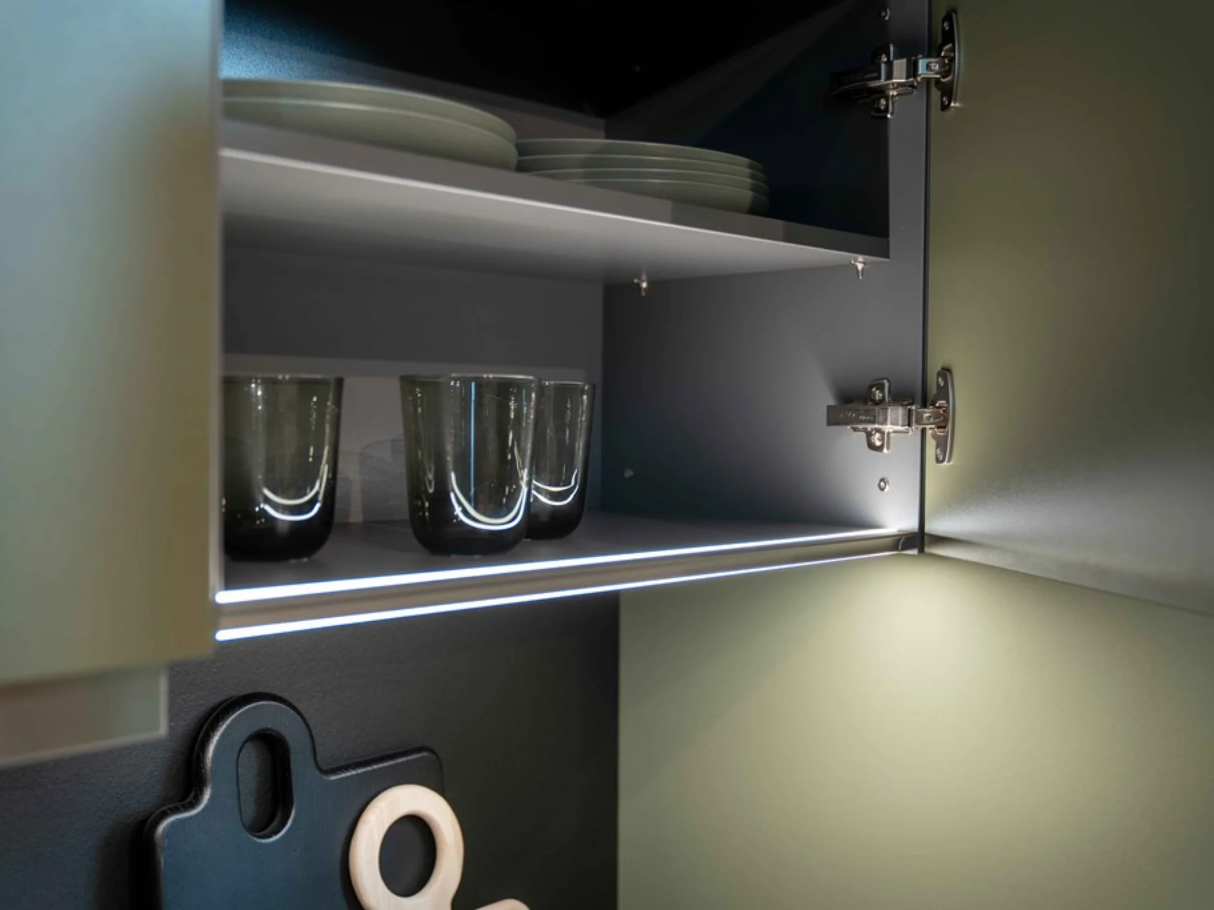 Ein geöffneter Küchenschrank mit Geschirr und Gläsern, beleuchtet von innen. Nolte Küchen.