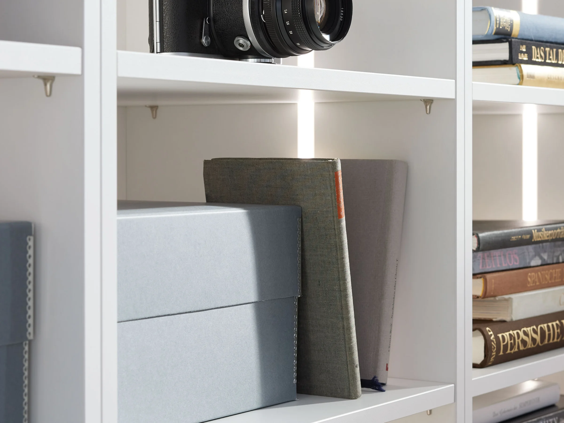 Ein weißes Regal mit Büchern und Boxen, Teil der Nolte Living Kollektion.