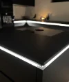 Eine moderne, schwarze Küche mit beleuchteter Insel, entworfen von Nolte Küchen.