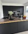 Eine moderne Küche mit dunklen Schränken und einer Insel, dekoriert mit Blumen, von Nolte Küchen.