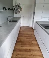 Cuisine moderne avec armoires blanches et sol en bois, Nolte Kitchen.