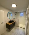Modernes Badezimmer mit schwarzem Waschbecken und runder Spiegelbeleuchtung, Nolte SPA.